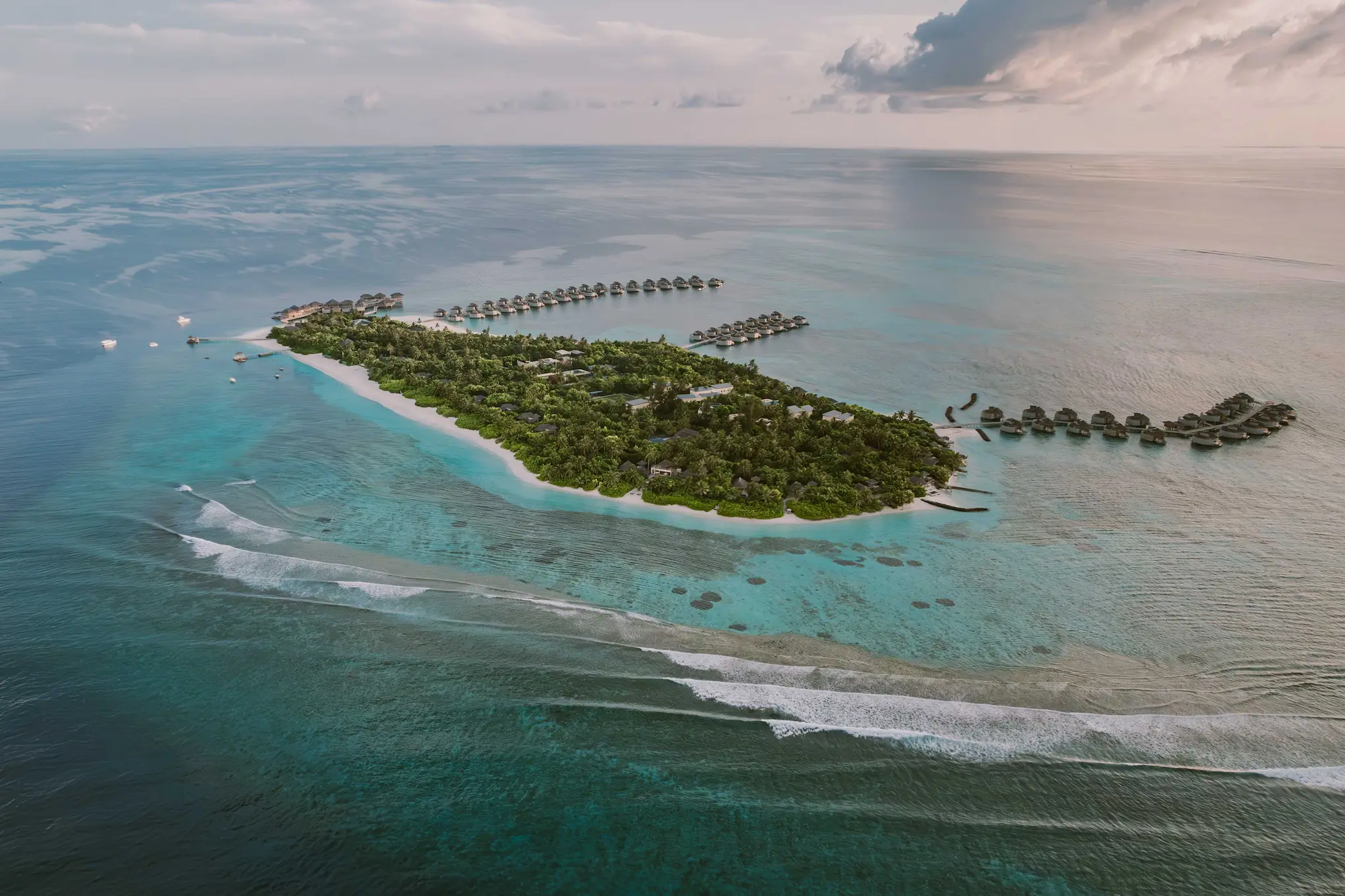 six senses laamu maldives aerial overall island view showing turquoise lagoon lush greenery and a serene elevated barefoot luxury atmosphere