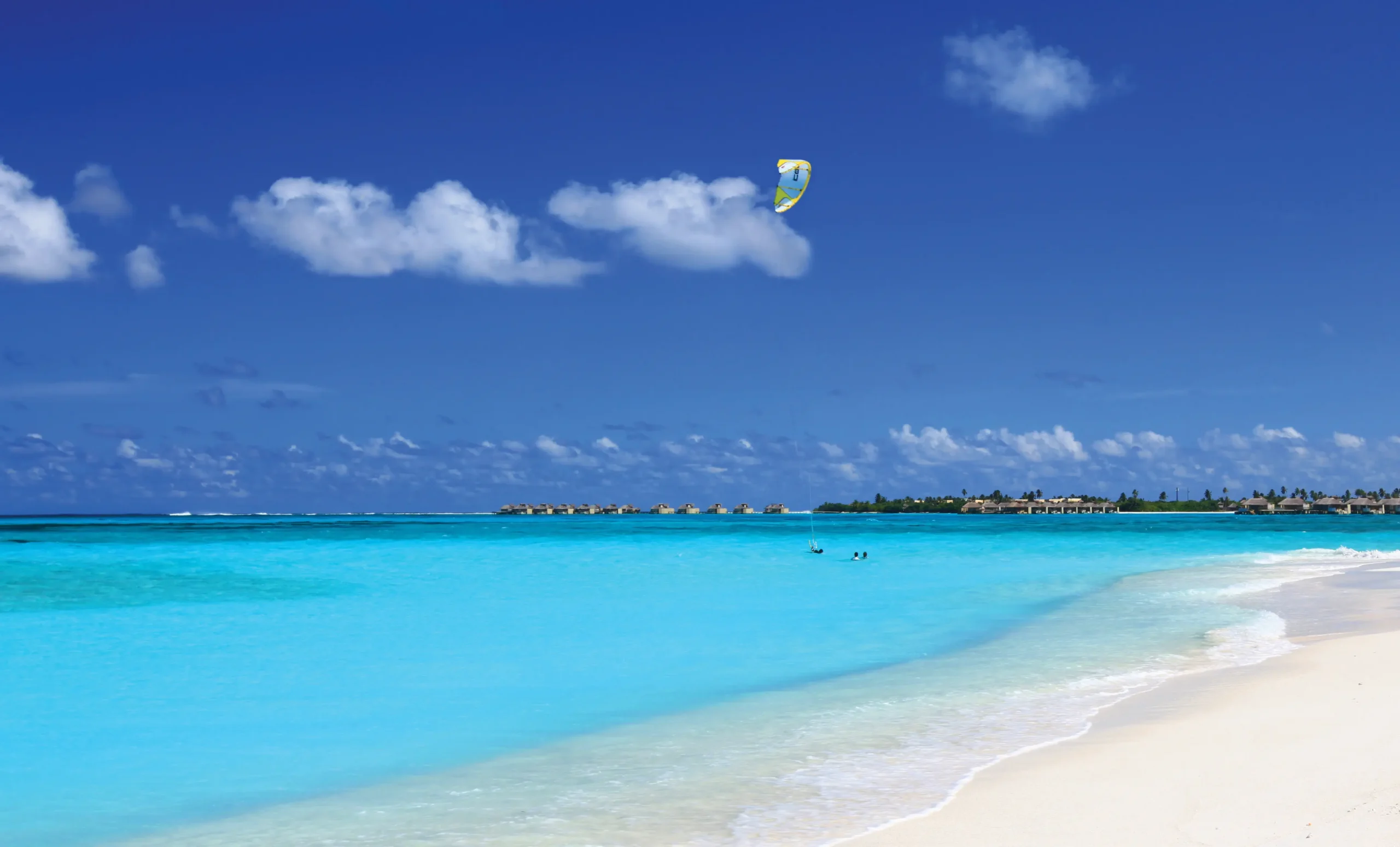six senses laamu maldives kite surfing over clear turquoise waters with gentle ocean breeze and a dynamic elevated barefoot luxury adventure atmosphere