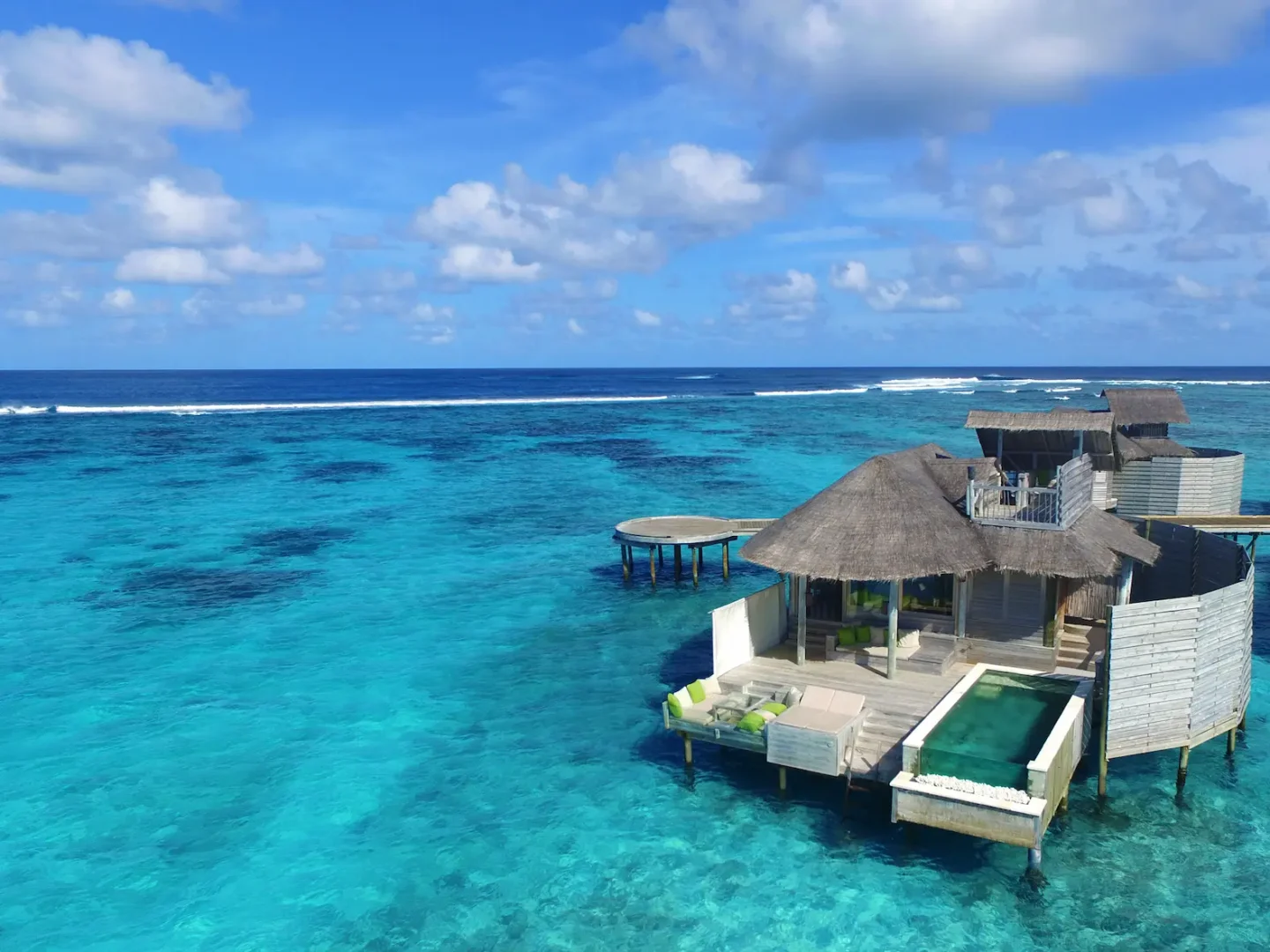 six senses laamu maldives laamu water villa with pool aerial view showing sweeping turquoise lagoon natural wood architecture and a serene elevated barefoot luxury atmosphere