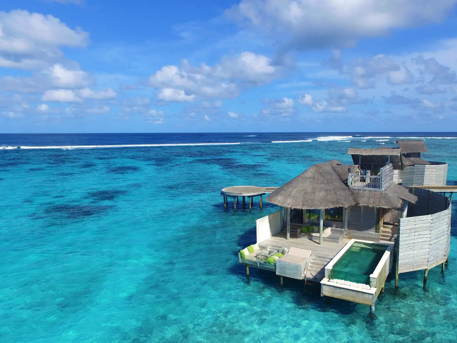 six senses laamu maldives laamu water villa with pool aerial view showing sweeping turquoise lagoon natural wood architecture and a serene elevated barefoot luxury atmosphere