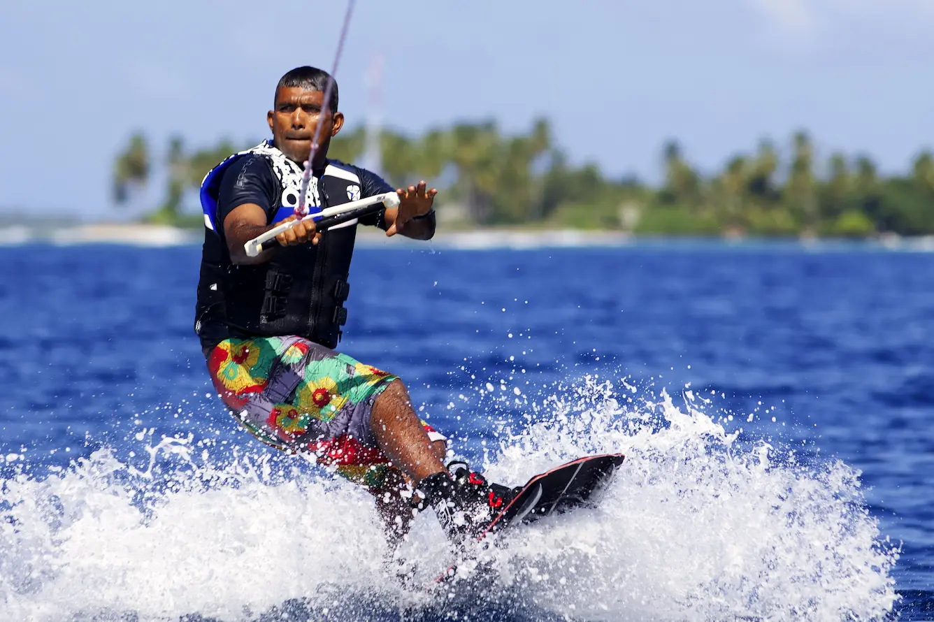 six senses laamu maldives wake boarding over clear turquoise waters with gentle ocean breeze and a dynamic elevated barefoot luxury adventure atmosphere