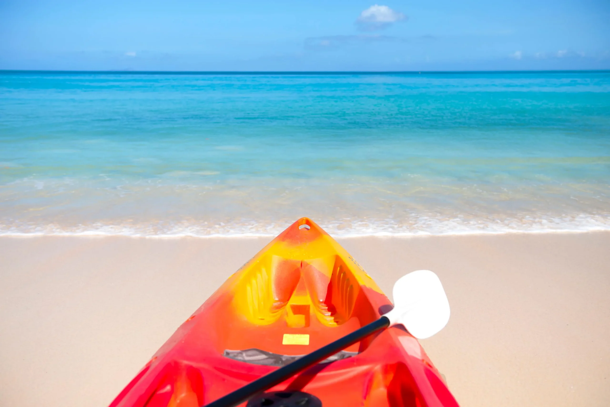A person kayaking on calm turquoise waters along a pristine beach in Seychelles, with tropical scenery in the background