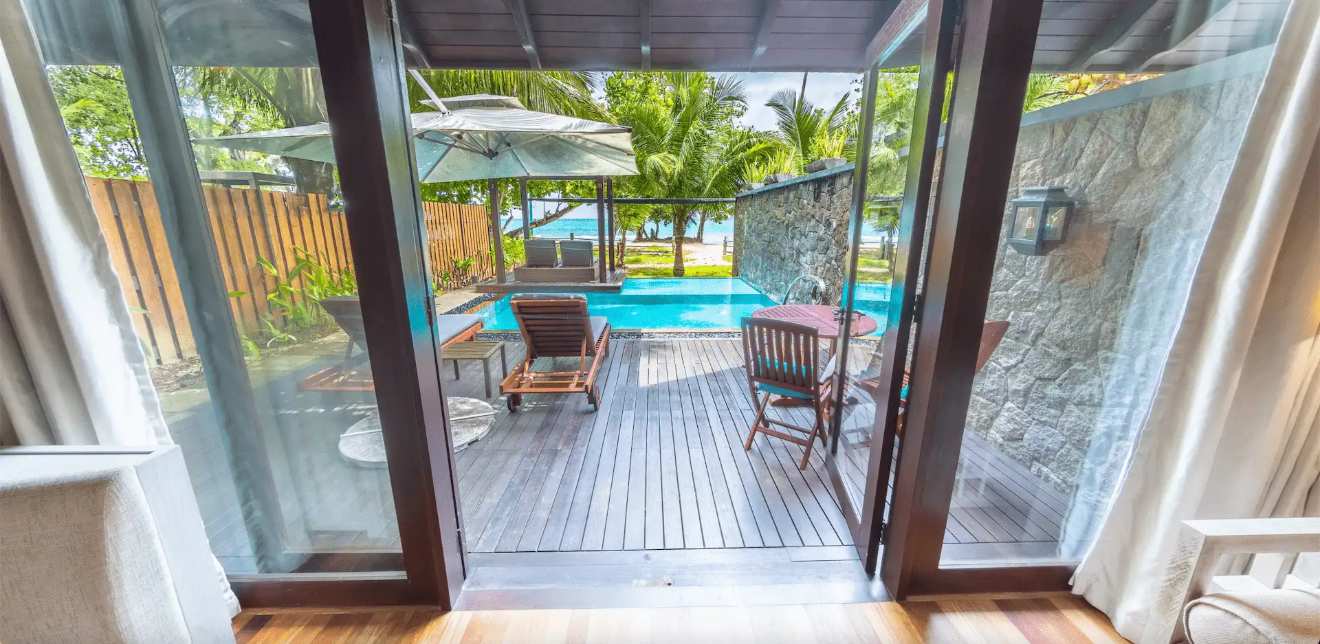 Private decking and pool of a beach pool villa in Seychelles, with sun loungers and tropical surroundings