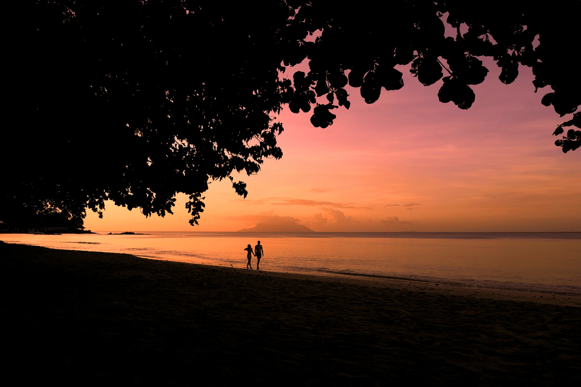 unset over Beau Vallon Beach in Seychelles, with golden skies, calm turquoise waters, and silhouettes of palm trees