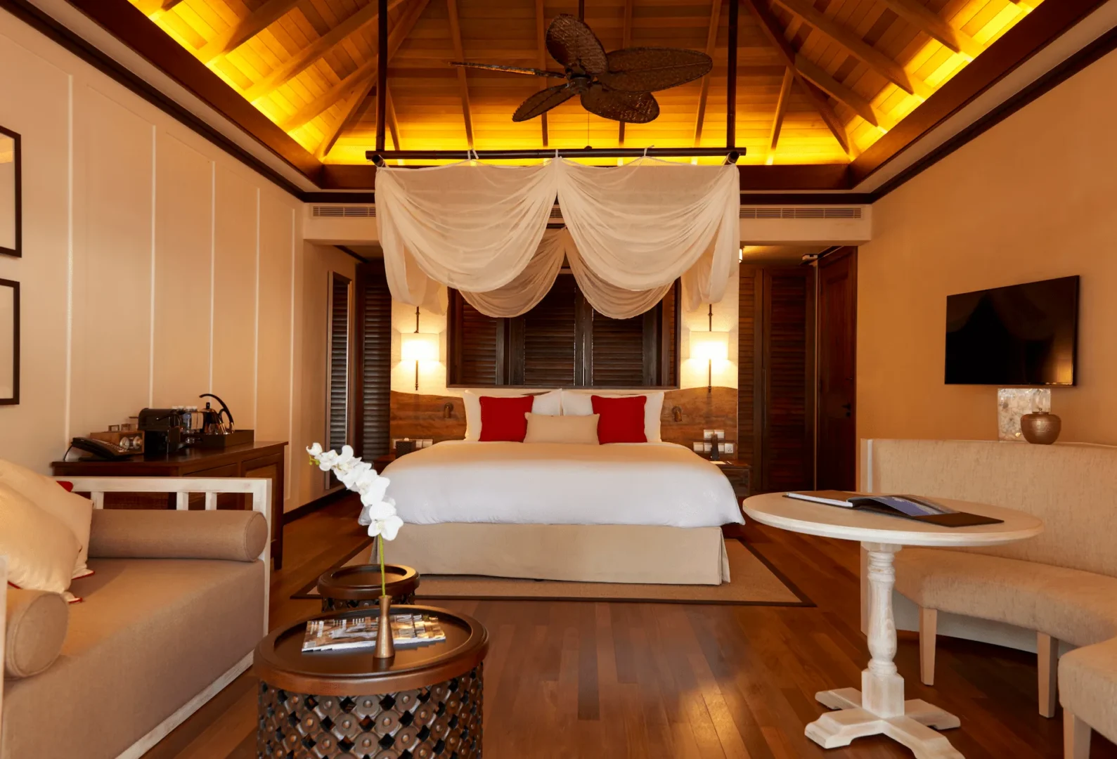Bedroom of a grand beach pool villa in Seychelles, featuring a large bed and views toward the private pool area