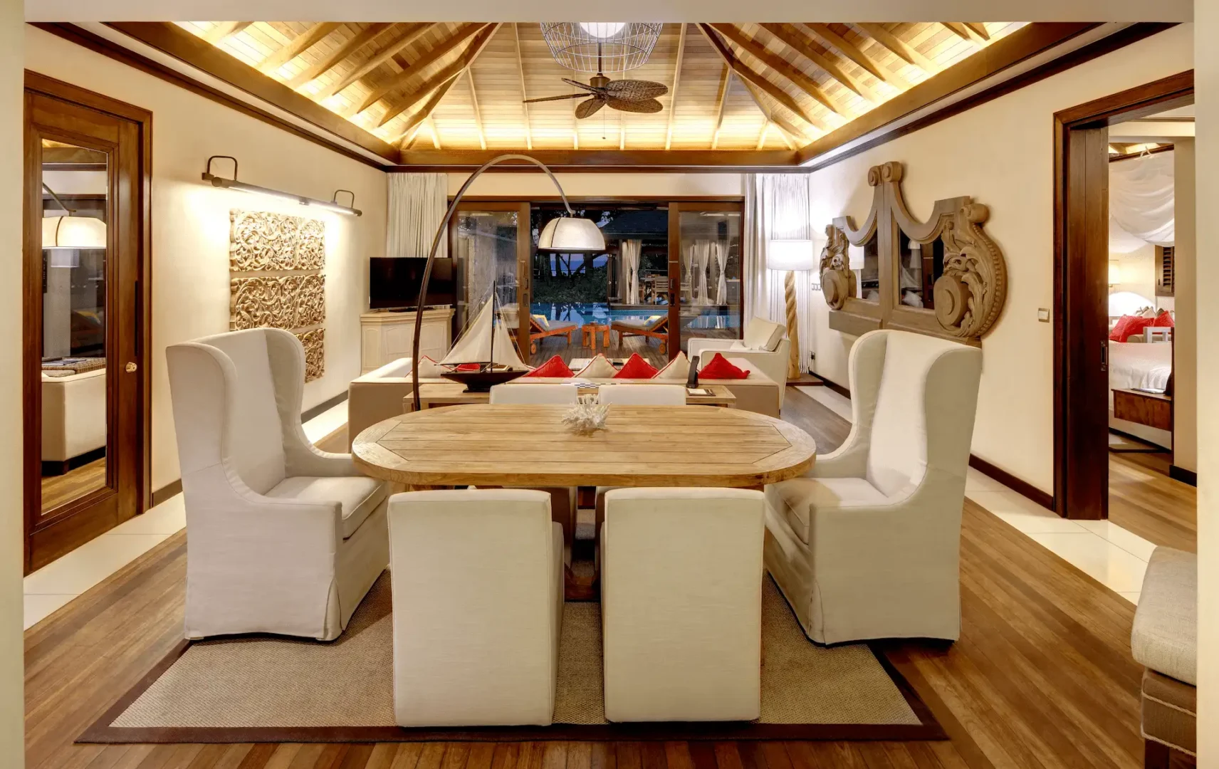Dining area of a grand beach pool villa in Seychelles, featuring a spacious table and seating with views of the private pool.