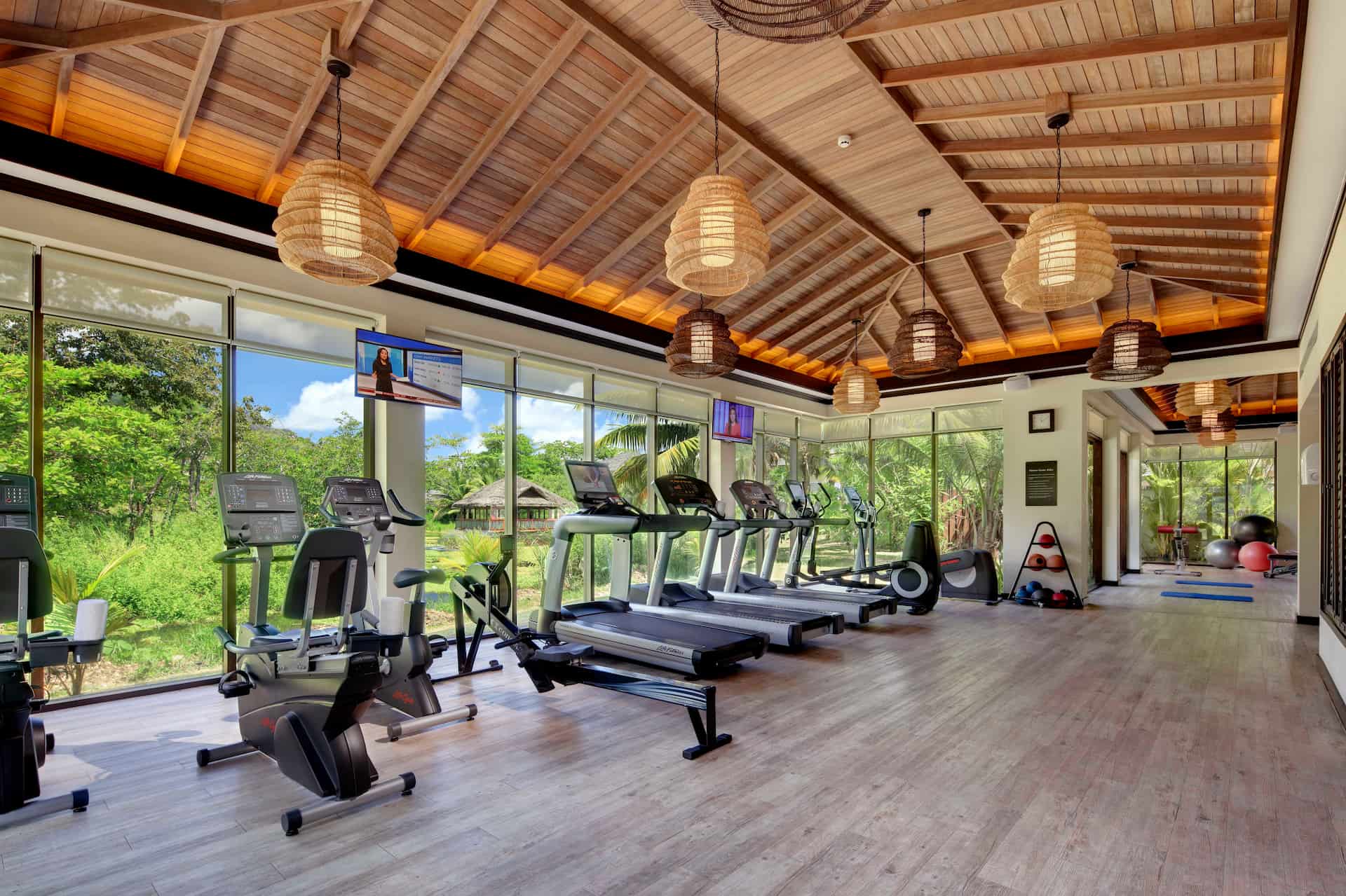 A modern gym in Seychelles with people exercising using treadmills, weights, and fitness equipment