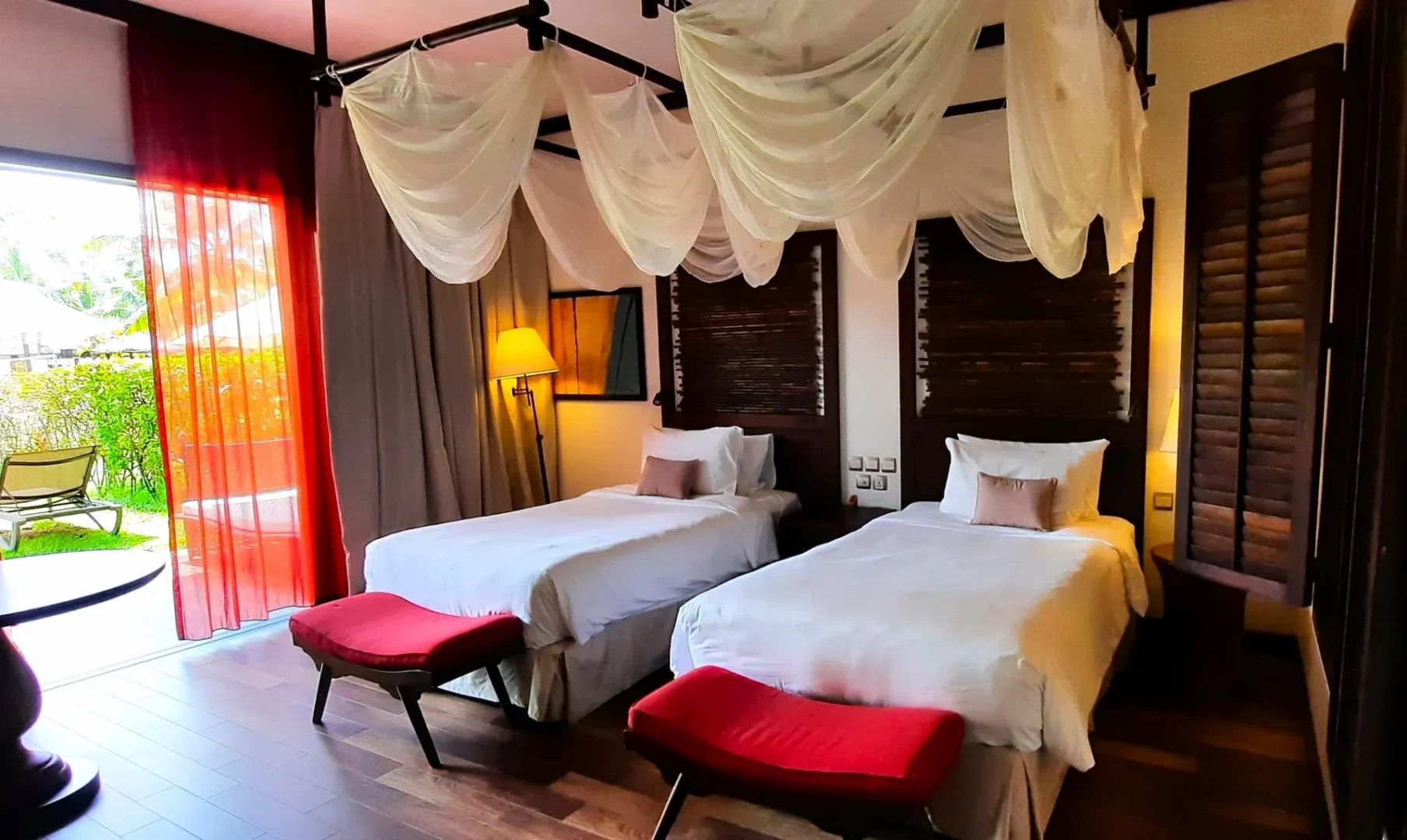 Junior suite with garden terrace in Seychelles featuring twin beds, tropical decor, and natural light from the terrace doors