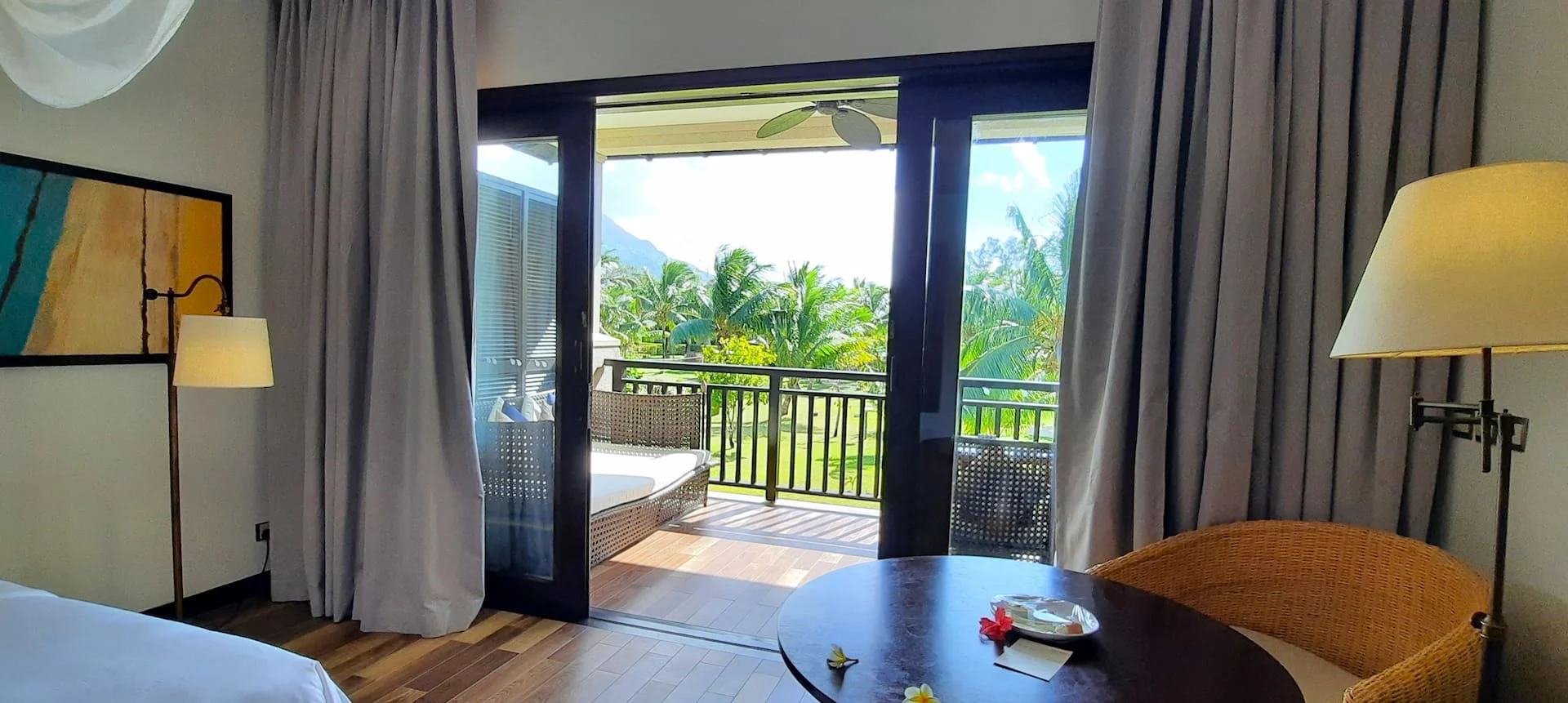 View from the balcony of a junior suite in Seychelles, overlooking turquoise waters, palm trees, and tropical scenery.