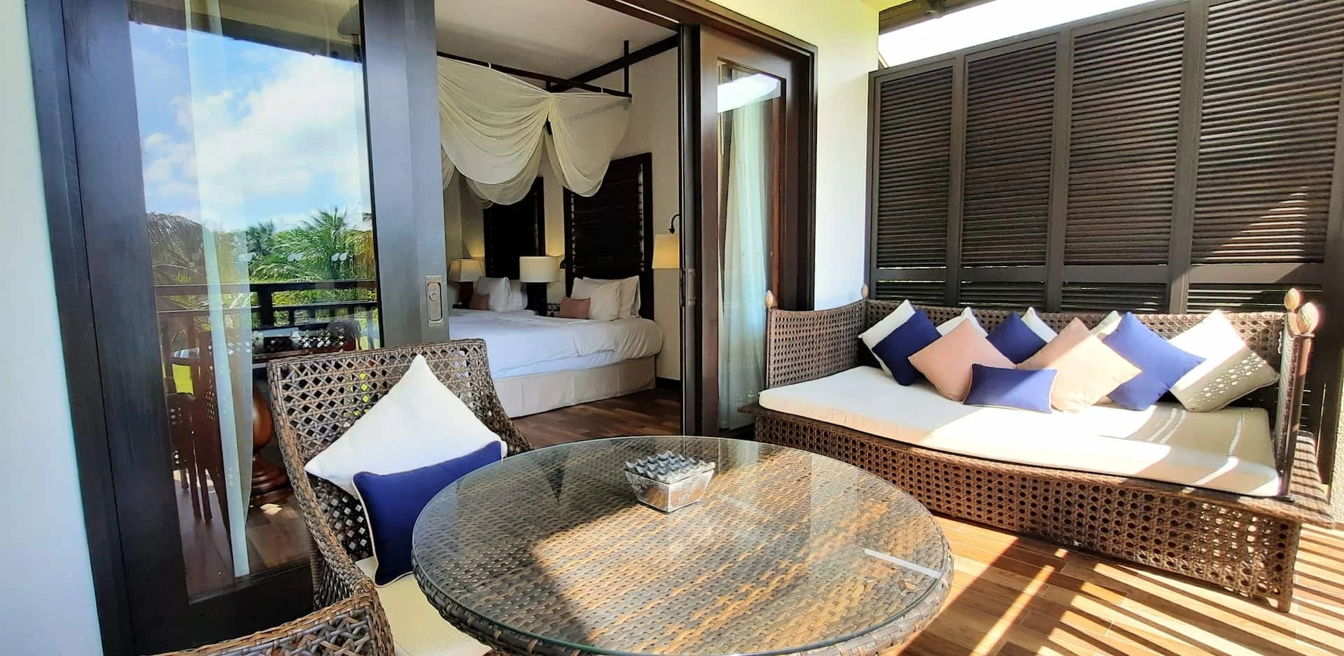 Outdoor balcony of a junior suite in Seychelles, overlooking tropical gardens and offering seating to enjoy the scenic views.