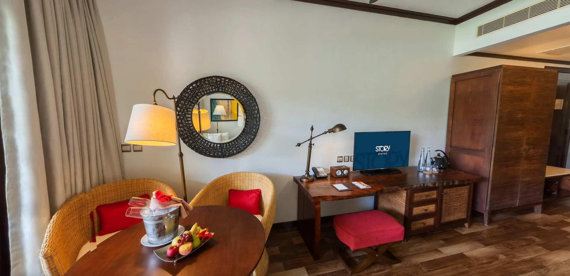 Junior suite in Seychelles featuring a table and seating area, with tropical-themed decor and natural light from the balcony.
