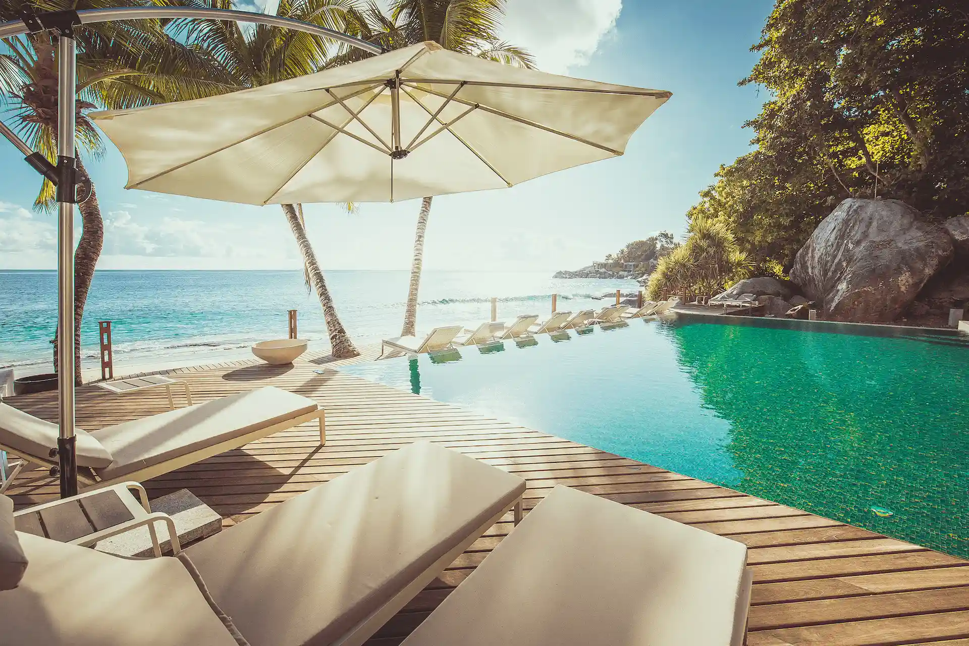 carana beach hotel seychelles swimming pool with ocean views, sun loungers, and tropical garden surroundings