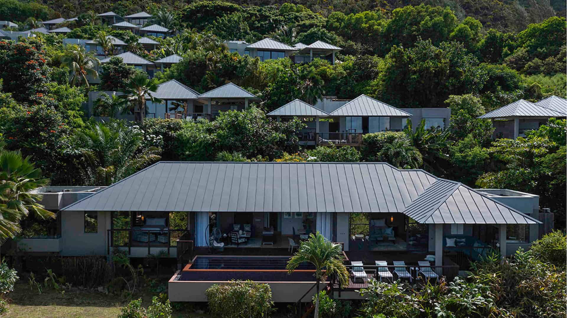 exterior view of two bedroom beachfront pool villa in seychelles with tropical birds flying over white sand beach and turquoise sea