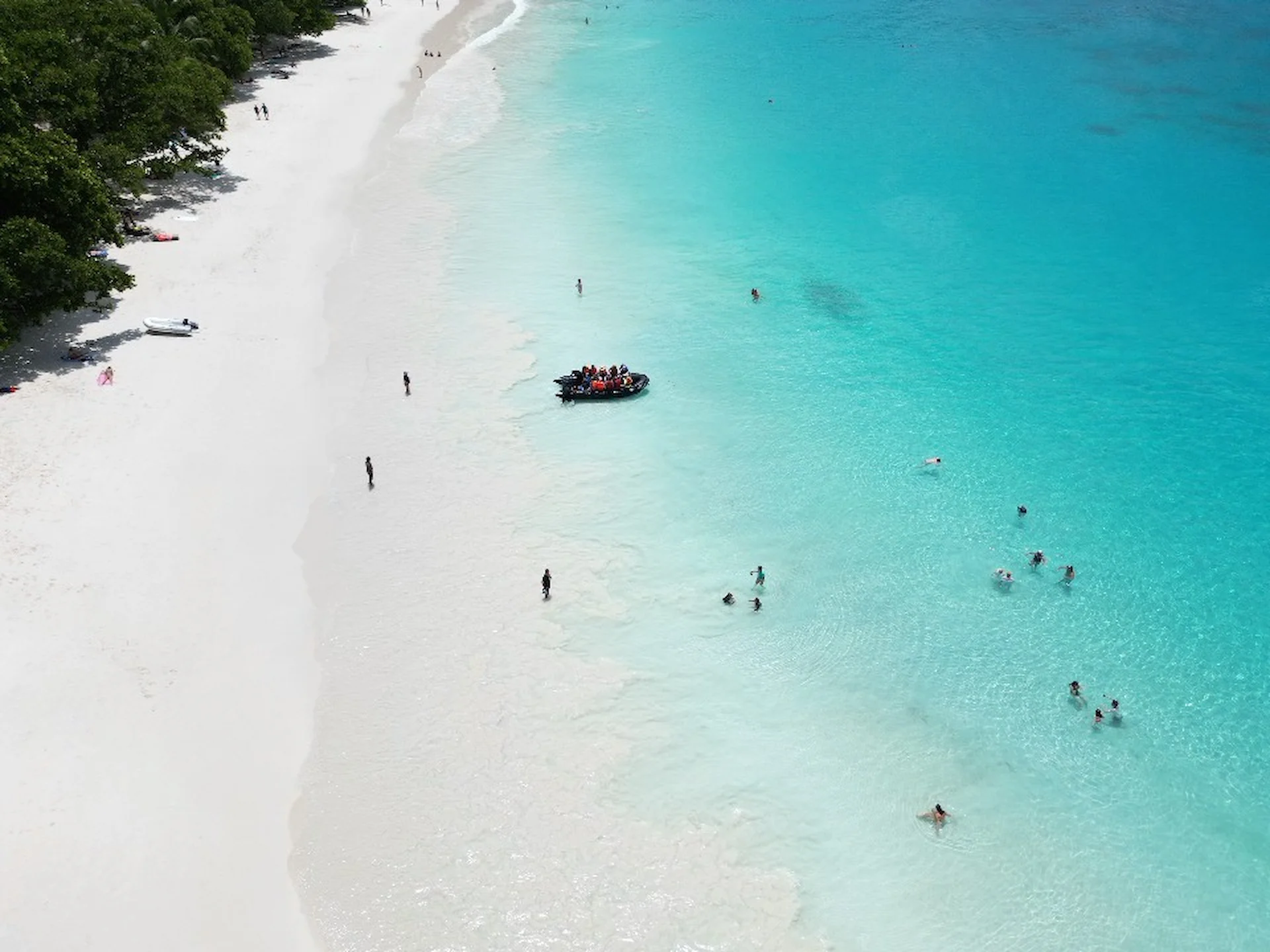 people relaxing on a beach during a cruise with Variety Cruises in the Seychelles, with white sand, turquoise waters, and a laid back tropical atmosphere