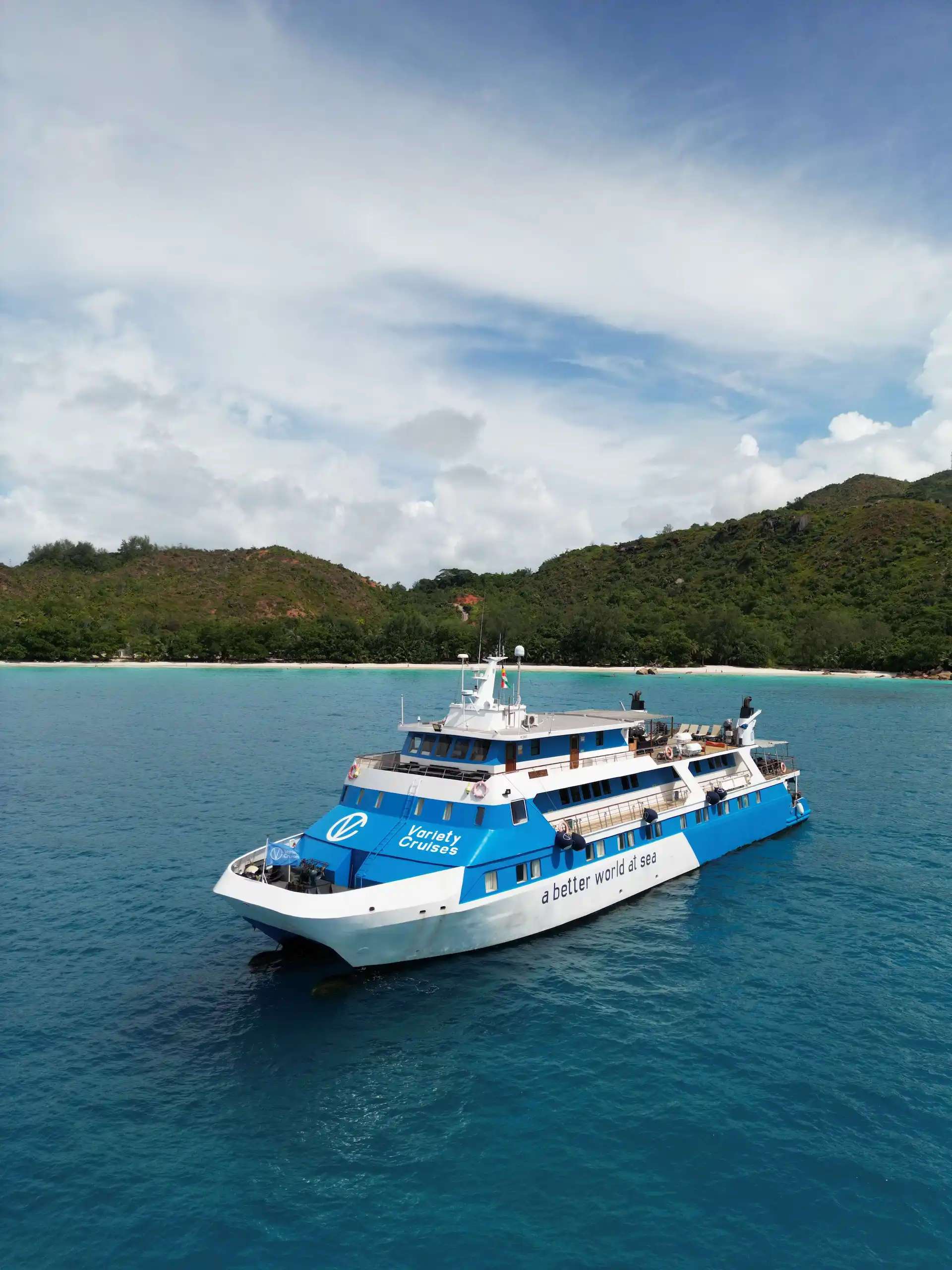 front view of a cruise boat from Variety Cruises sailing through clear turquoise waters in the Seychelles surrounded by tropical islands