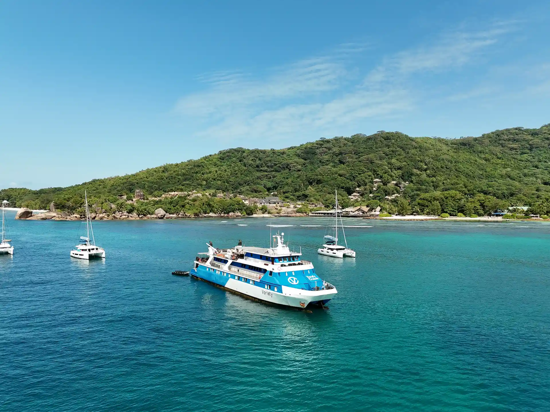 cruise boat at sea from Variety Cruises sailing across calm turquoise waters in the Seychelles with tropical islands in the distance