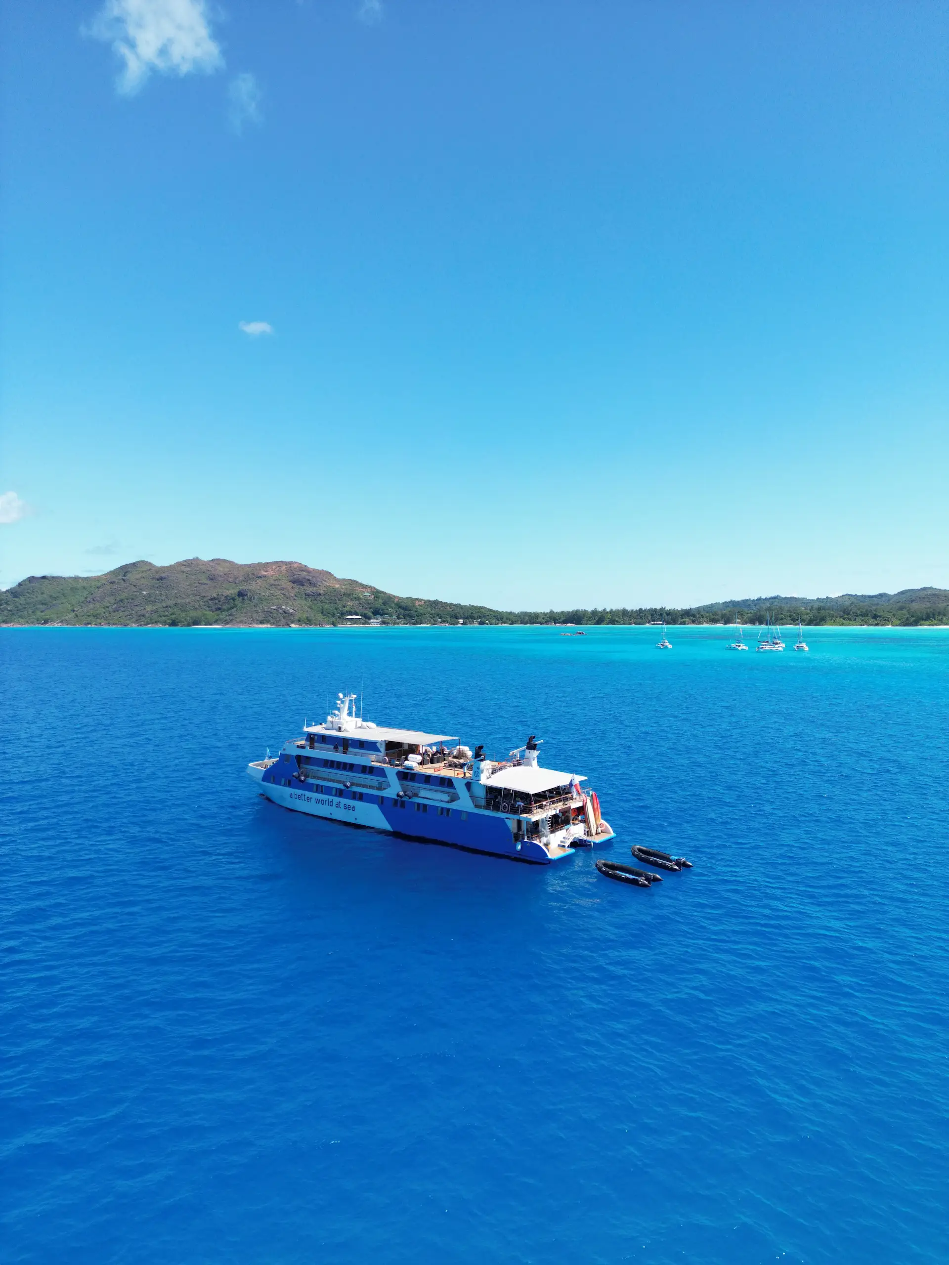 cruise boat from Variety Cruises sailing in the Seychelles with passengers onboard and tropical island scenery in the background