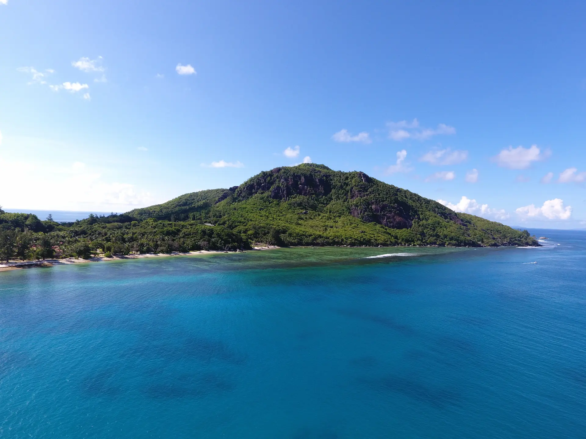 aerial view of a tropical island during a cruise with Variety Cruises in the Seychelles showing lush greenery, white sand beaches, and surrounding turquoise ocean