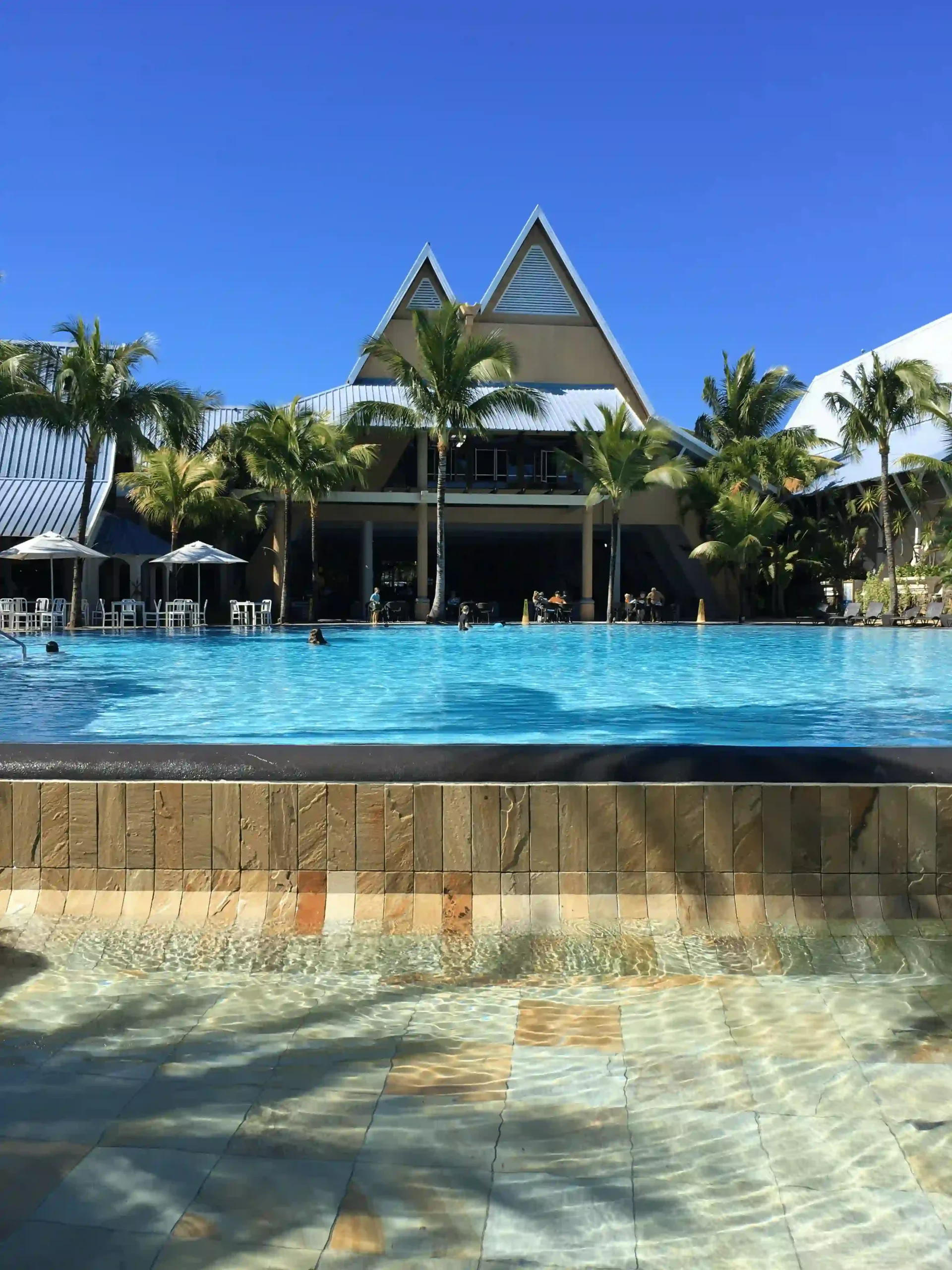 victoria mauritius pool with clear water surrounded by sun loungers and tropical plants