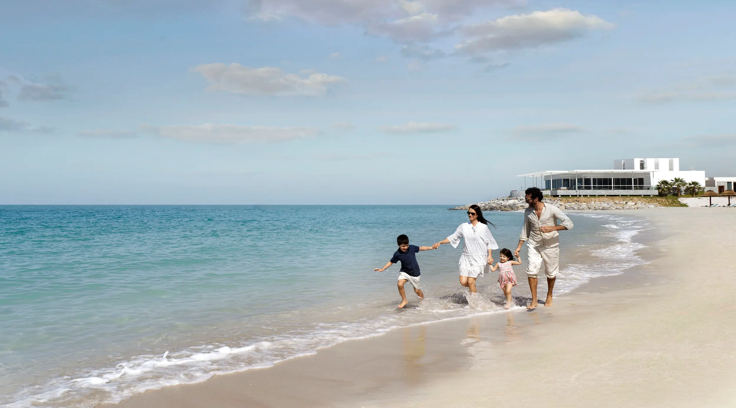 intercontinental ras al khaimah resort spa family on beach enjoying relaxed time together along the shoreline in a serene coastal setting