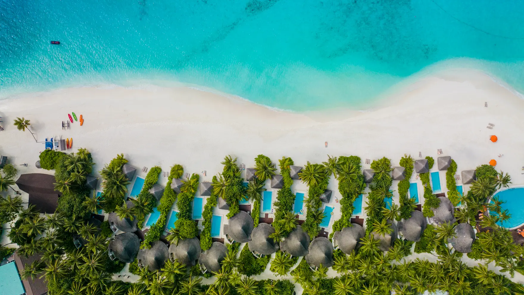 sun siyam vilu reef maldives aerial beach villas lining the white sand shoreline with lush tropical surroundings