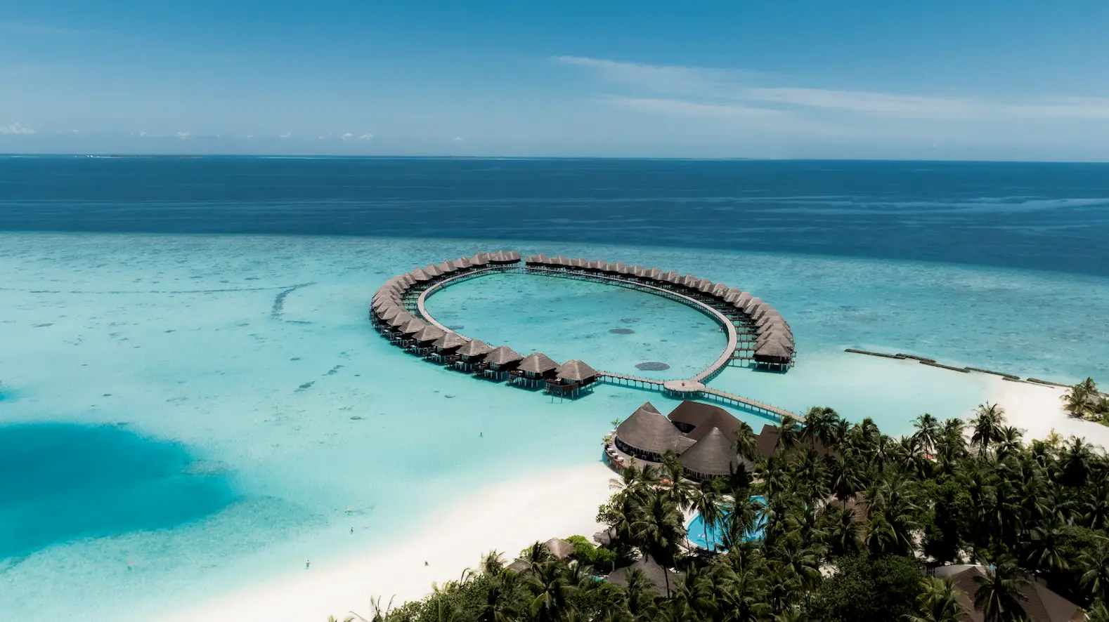 sun siyam vilu reef maldives aerial water villas set above a turquoise lagoon with graceful curved boardwalks