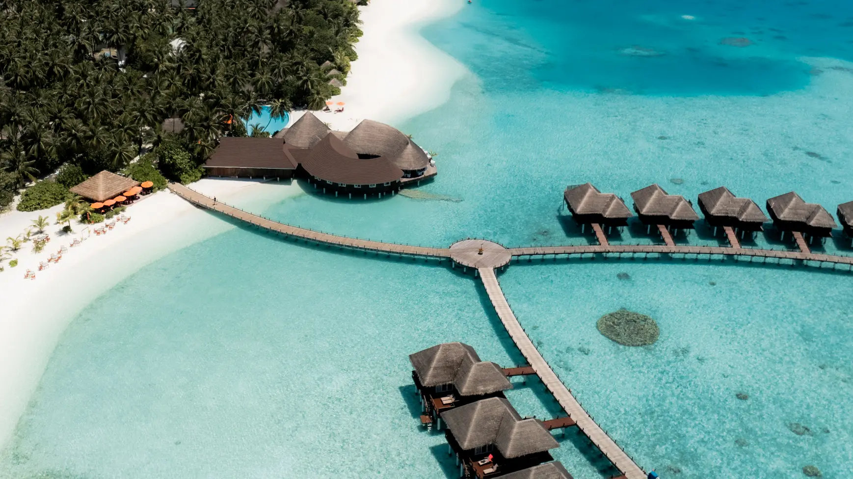 sun siyam vilu reef maldives aerial view showcasing the island surrounded by turquoise lagoon and white sand shoreline