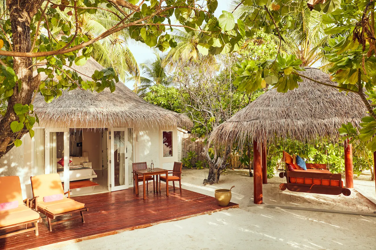 sun siyam vilu reef maldives jacuzzi deluxe beach villa exterior set along a peaceful white sand beach framed by lush tropical greenery