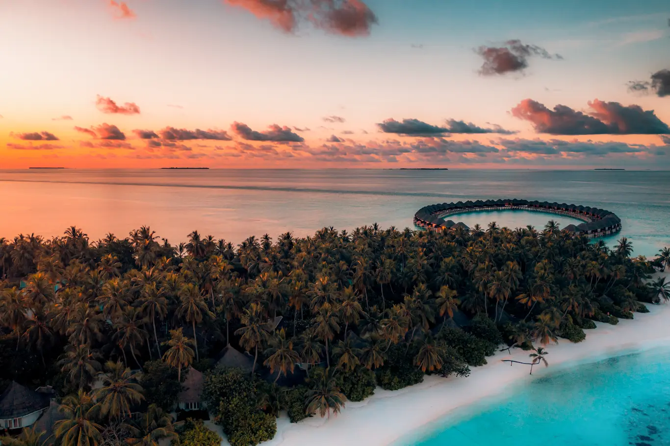 sun siyam vilu reef maldives sunset over the lagoon casting warm golden light across the island