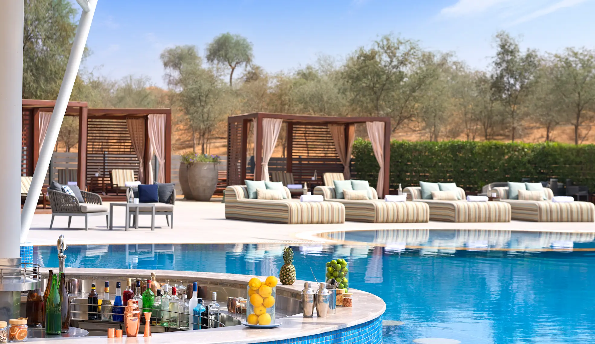 the ritzcarlton al wadi desert oasis pool bar offering a relaxed poolside bar setting surrounded by the desert landscape
