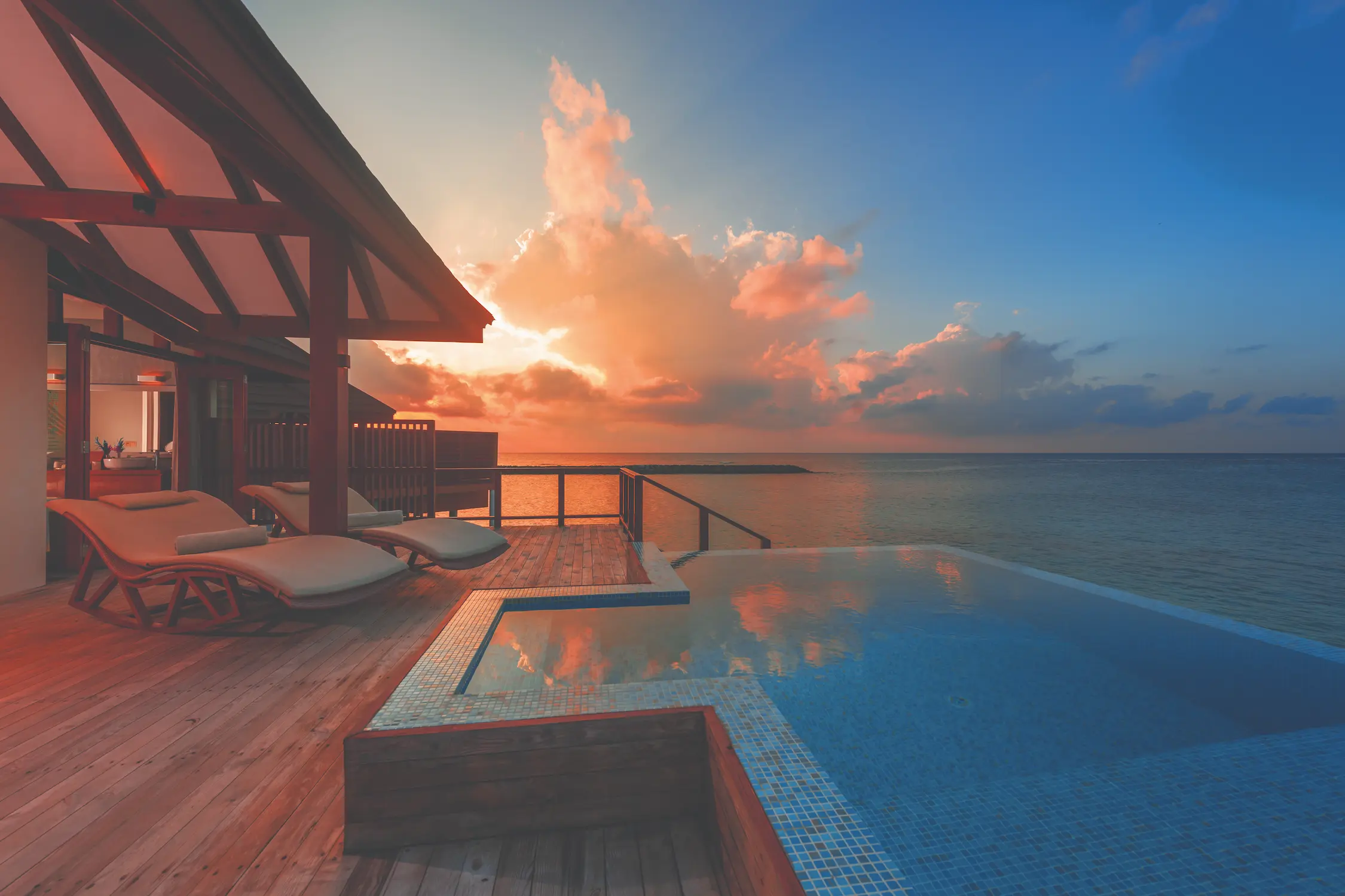 luxury water villa with private pool at sunset at varu by atmosphere maldives set over the turquoise lagoon