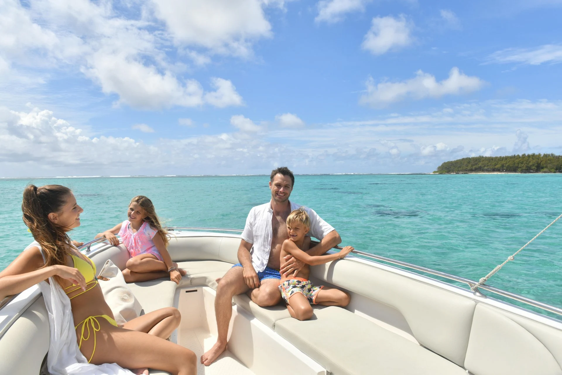 family on a boat trip at shandrani mauritius sailing across turquoise lagoon with tropical coastline and clear skies