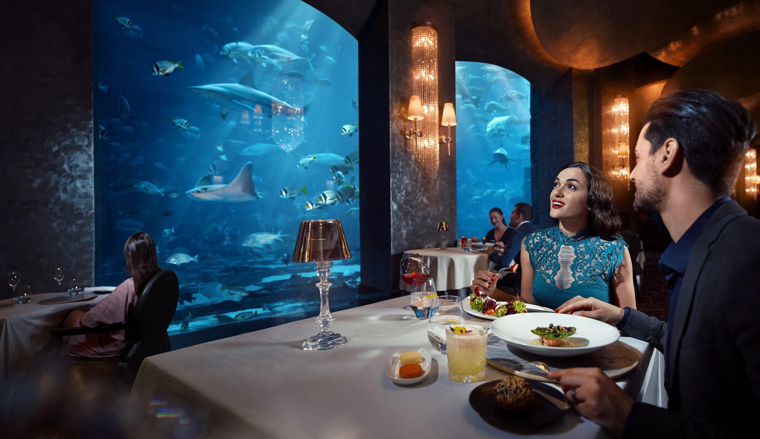 atlantis the palm ossiano dining couple at dinner surrounded by floor to ceiling aquarium views creating an intimate fine dining experience in dubai