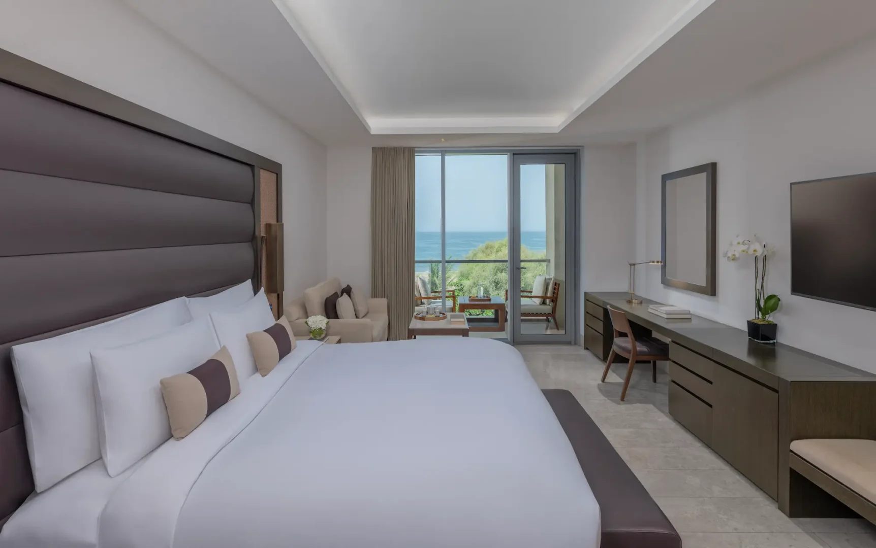kempinski hotel muscat muscat deluxe sea view room bed with crisp linens and elegant coastal interior