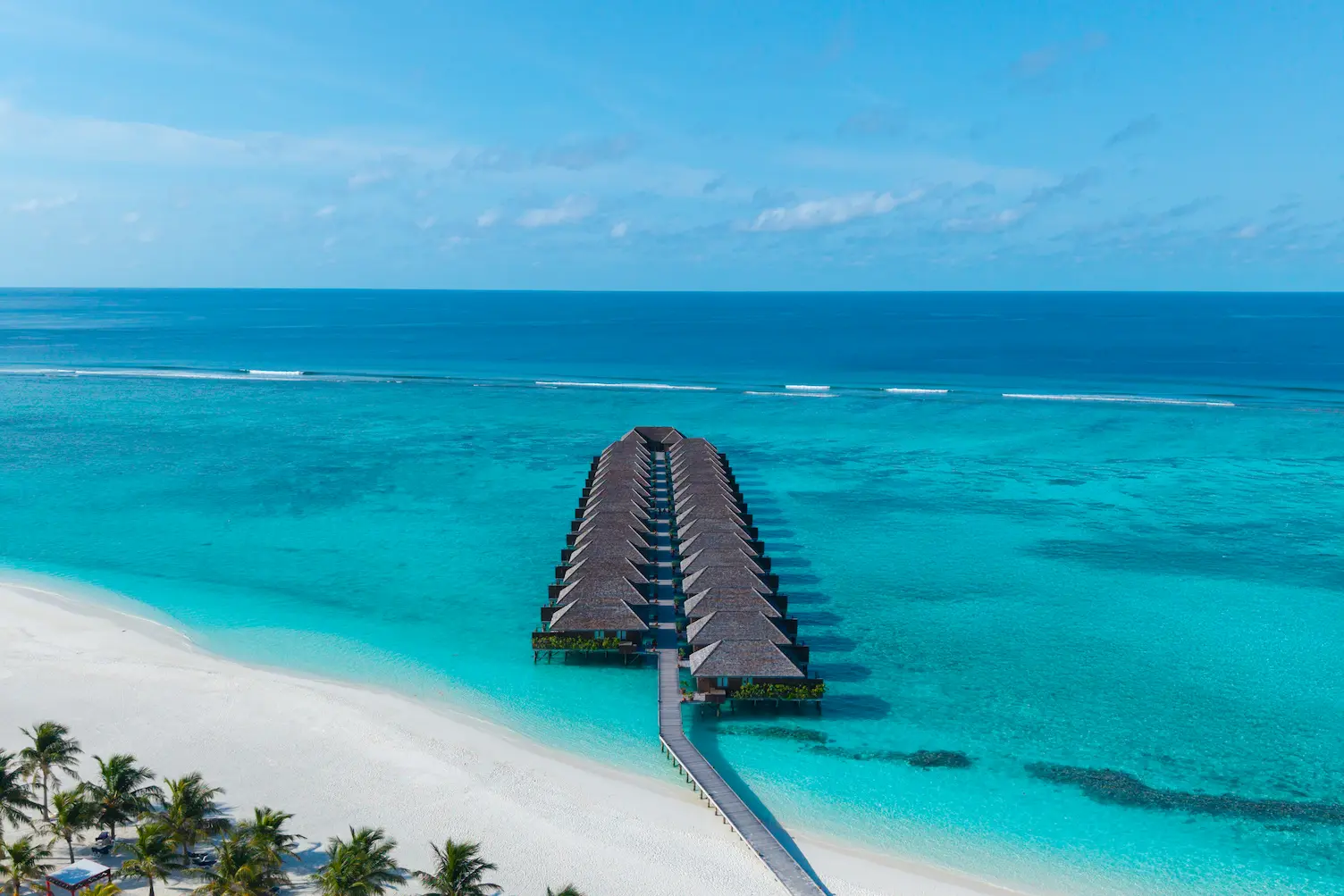 meeru maldives ocean villa aerial view showcasing overwater villas set above a turquoise lagoon with private decks in a serene island setting in maldives