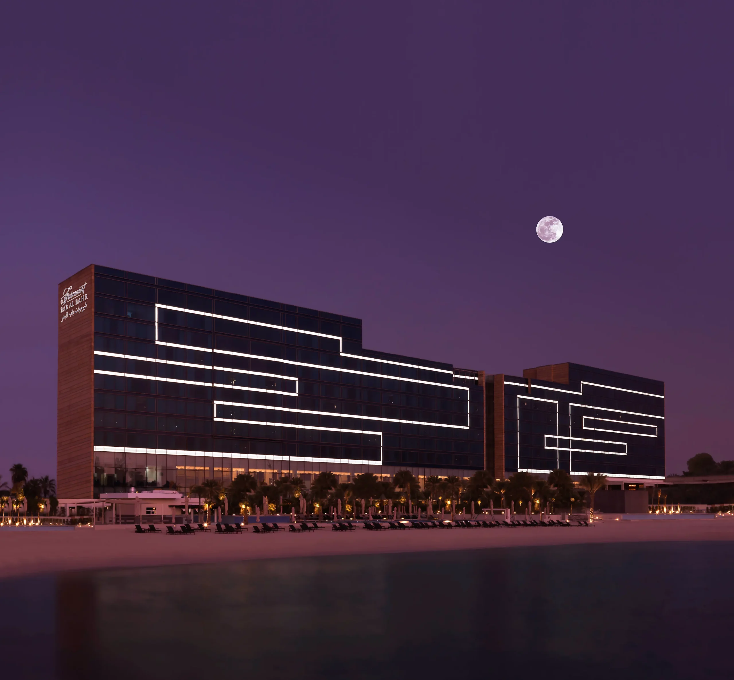 Fairmont Bab Al Bahr Abu Dhabi illuminated at night overlooking Abu Dhabi Creek and the Sheikh Zayed Grand Mosque