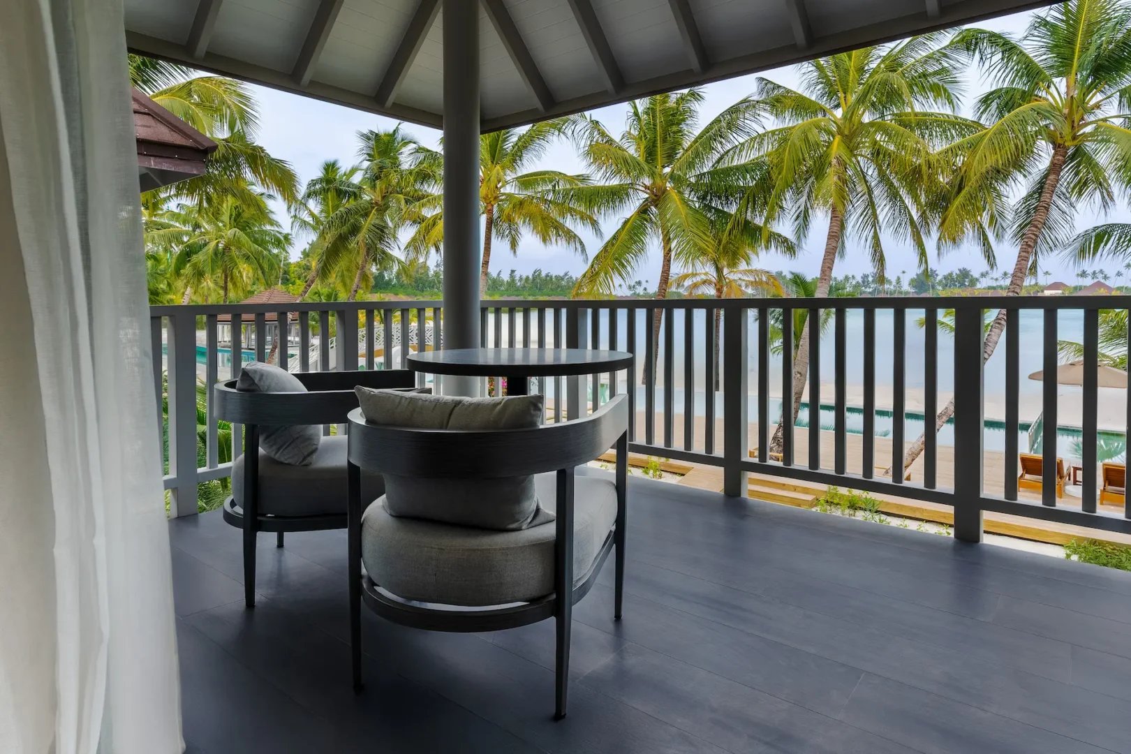 private balcony at a beach pavilion at sun siyam olhuveli maldives with outdoor seating near the beach