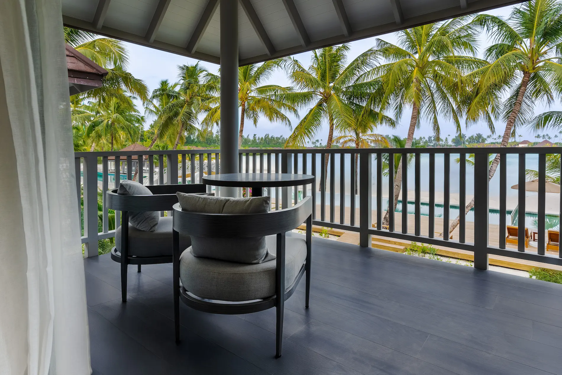 private balcony at a beach pavilion at sun siyam olhuveli maldives with outdoor seating near the beach