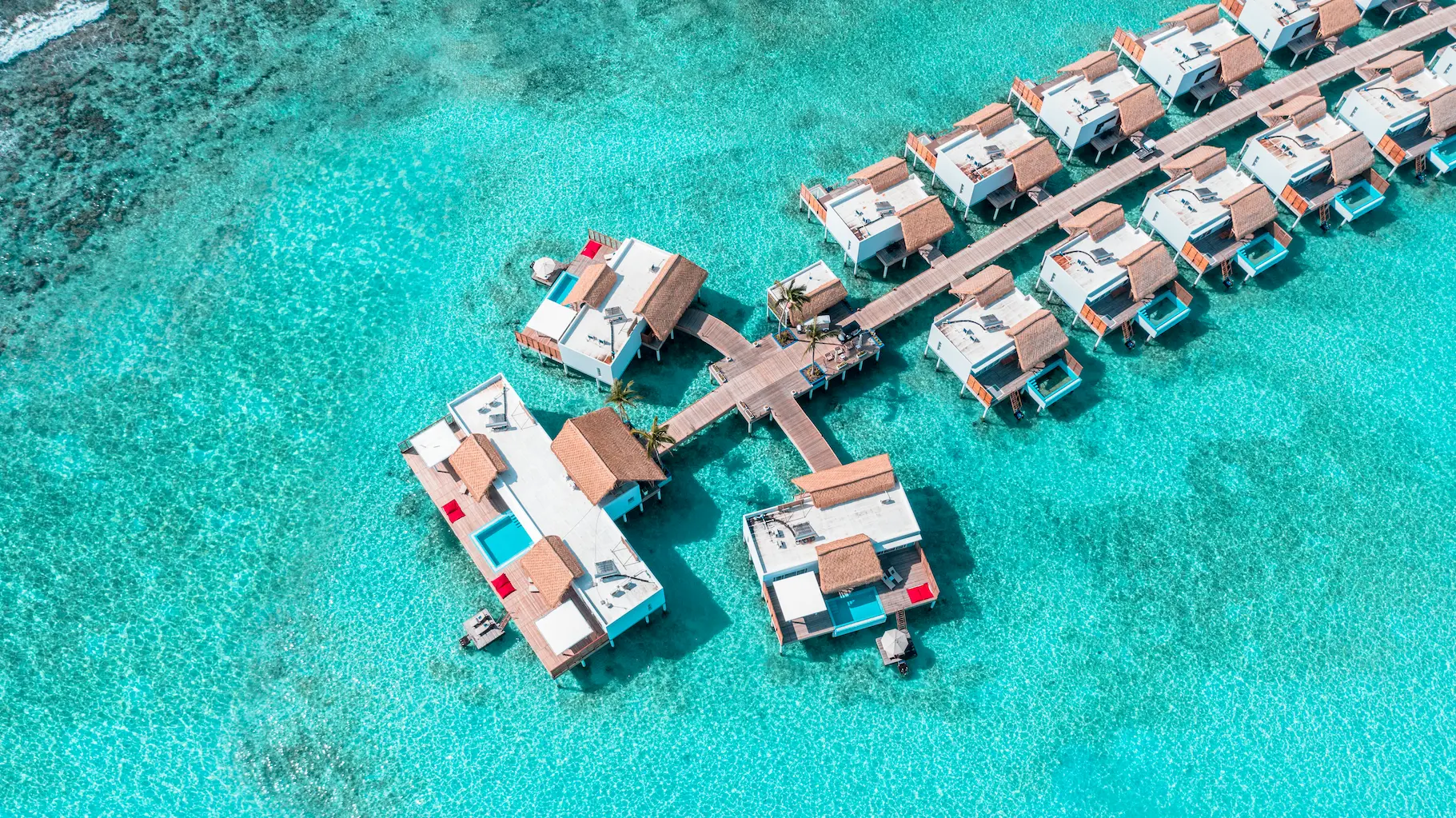 aerial view of superior water villas with pool at emerald maldives resort & spa in the maldives extending across the lagoon with private pools, overwater terraces and direct ocean access