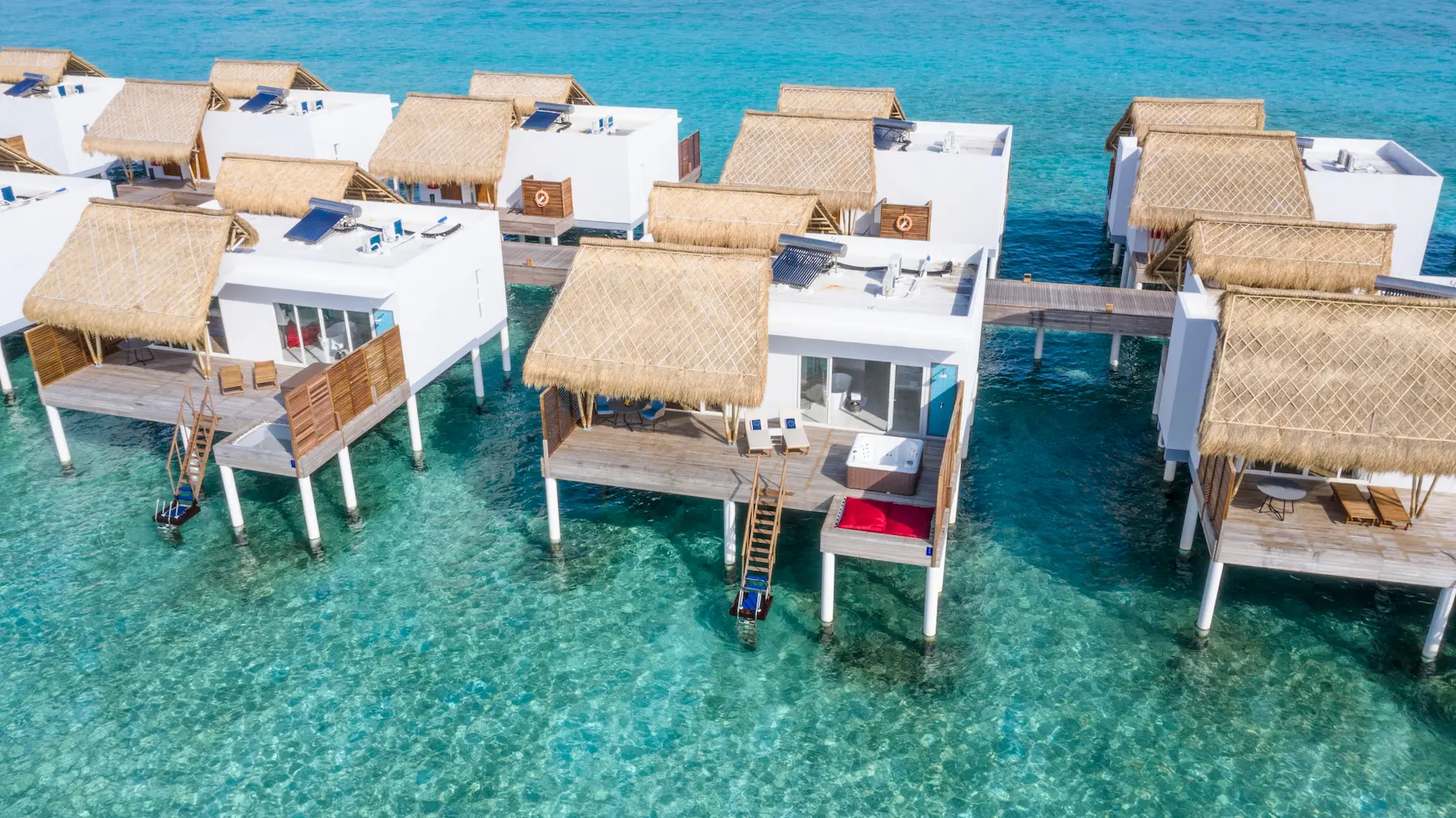 aerial view of jacuzzi water villas at emerald maldives resort & spa in the maldives extending across the lagoon with private outdoor jacuzzis and direct ocean access