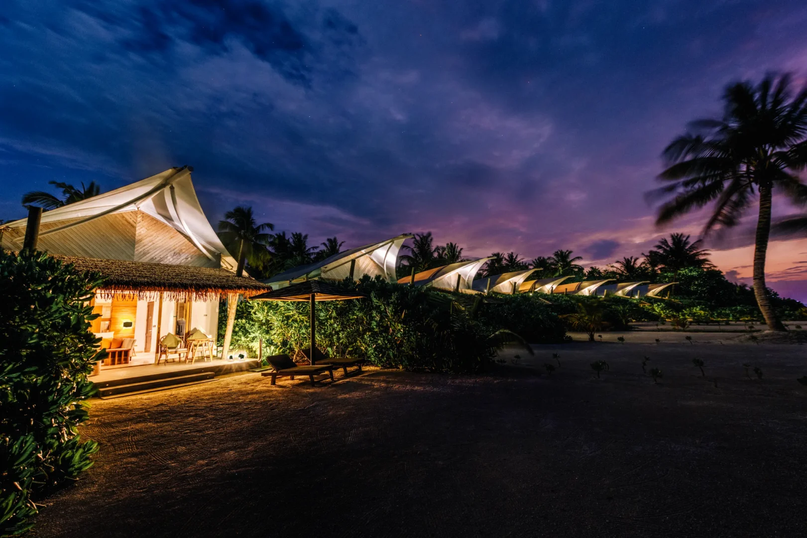 Beach Bungalow illuminated at night at Cinnamon Hakuraa Huraa Maldives, Maldives.