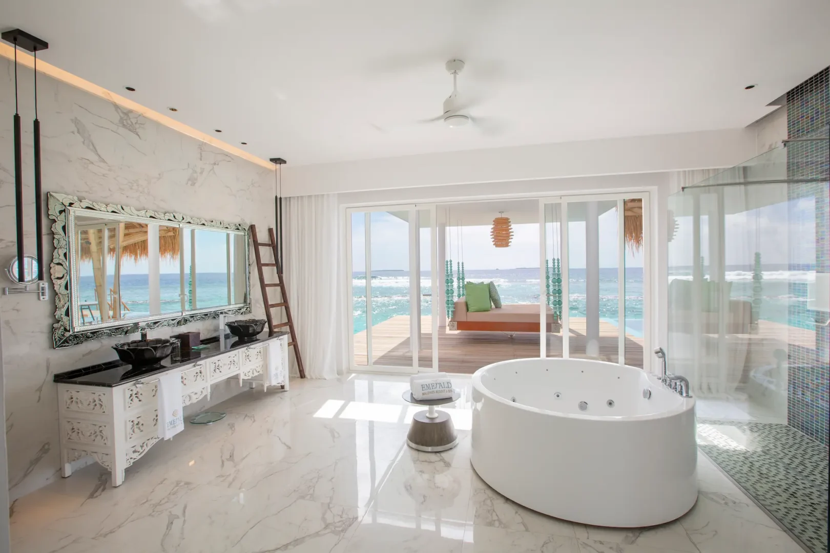 bathroom in a superior water villa with pool at emerald maldives resort & spa in the maldives featuring a bathtub, walk-in shower, spacious vanity area and views towards the private overwater terrace and pool