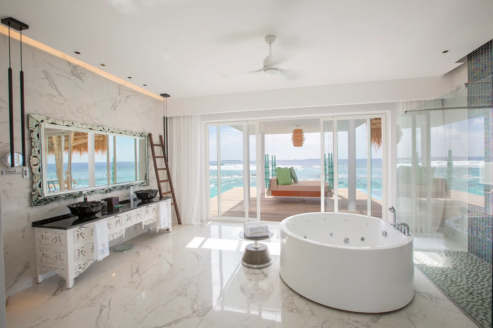 bathroom in a superior water villa with pool at emerald maldives resort & spa in the maldives featuring a bathtub, walk-in shower, spacious vanity area and views towards the private overwater terrace and pool