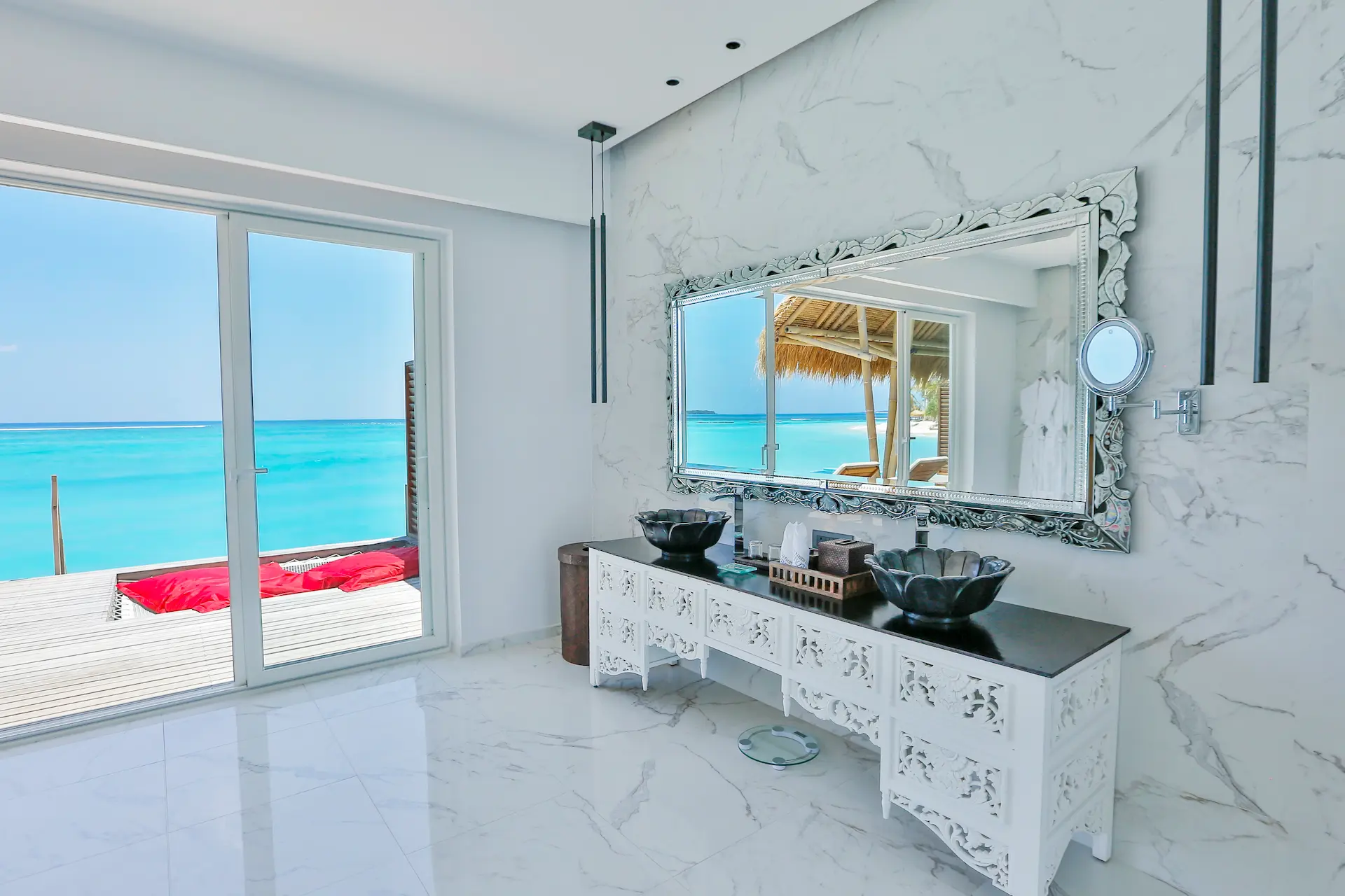 vanity area in a water villa at emerald maldives resort & spa in the maldives featuring double washbasins, contemporary finishes and views towards the overwater accommodation