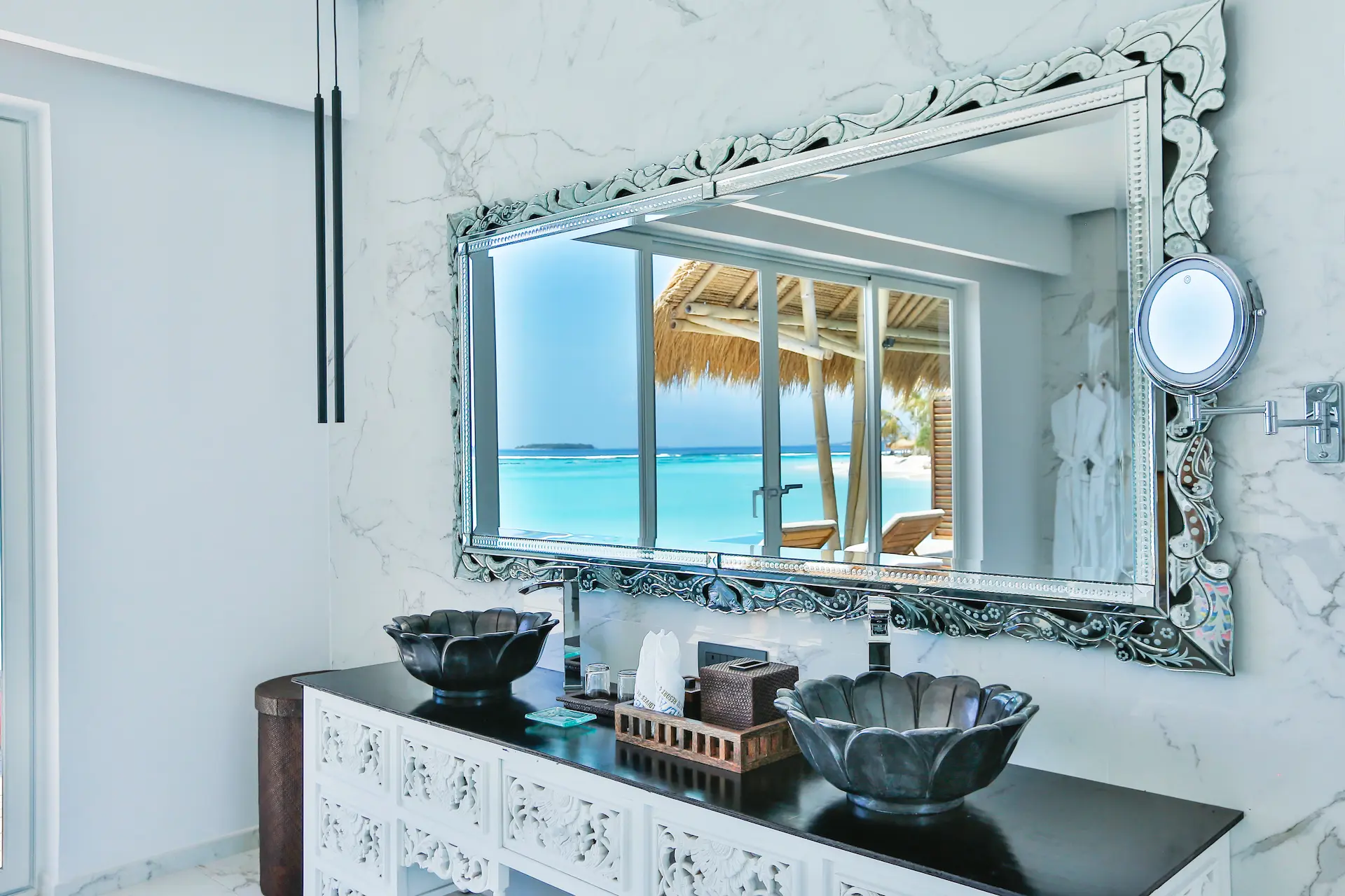 vanity area in a water villa with pool at emerald maldives resort & spa in the maldives featuring double washbasins, contemporary finishes and views towards the overwater accommodation