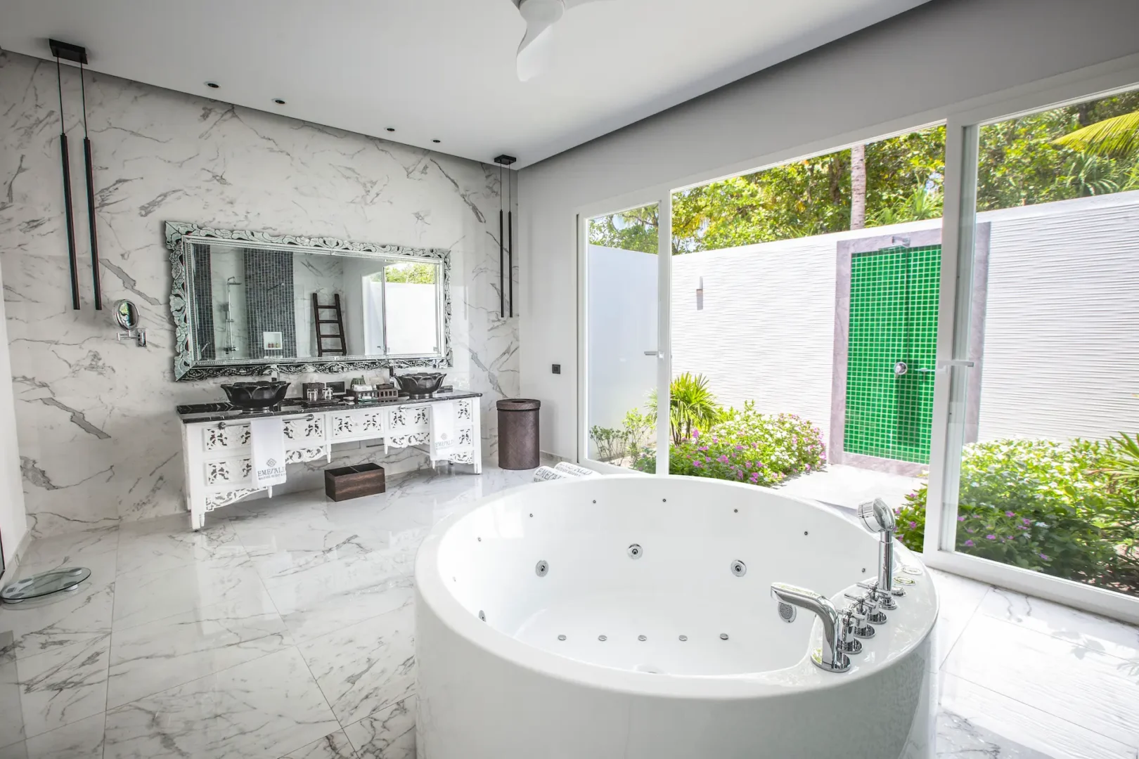 bathroom in a superior beach villa with pool at emerald maldives resort & spa in the maldives featuring a bathtub, walk-in shower, outdoor shower and spacious vanity area