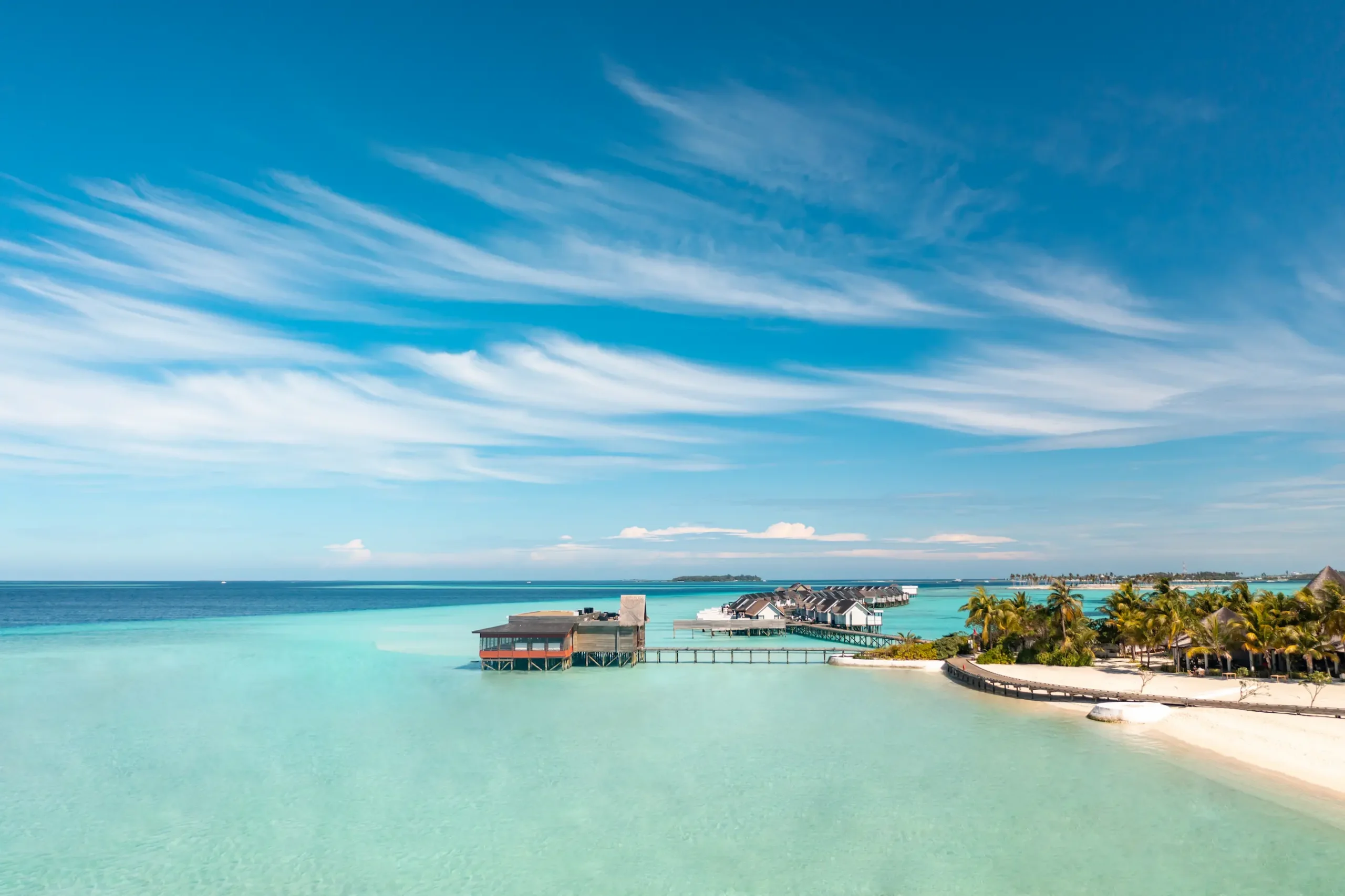Aerial view of the central hub area at OZEN LIFE MAADHOO, showcasing the island's main facilities, restaurants, bars, pool areas and beachfront surroundings