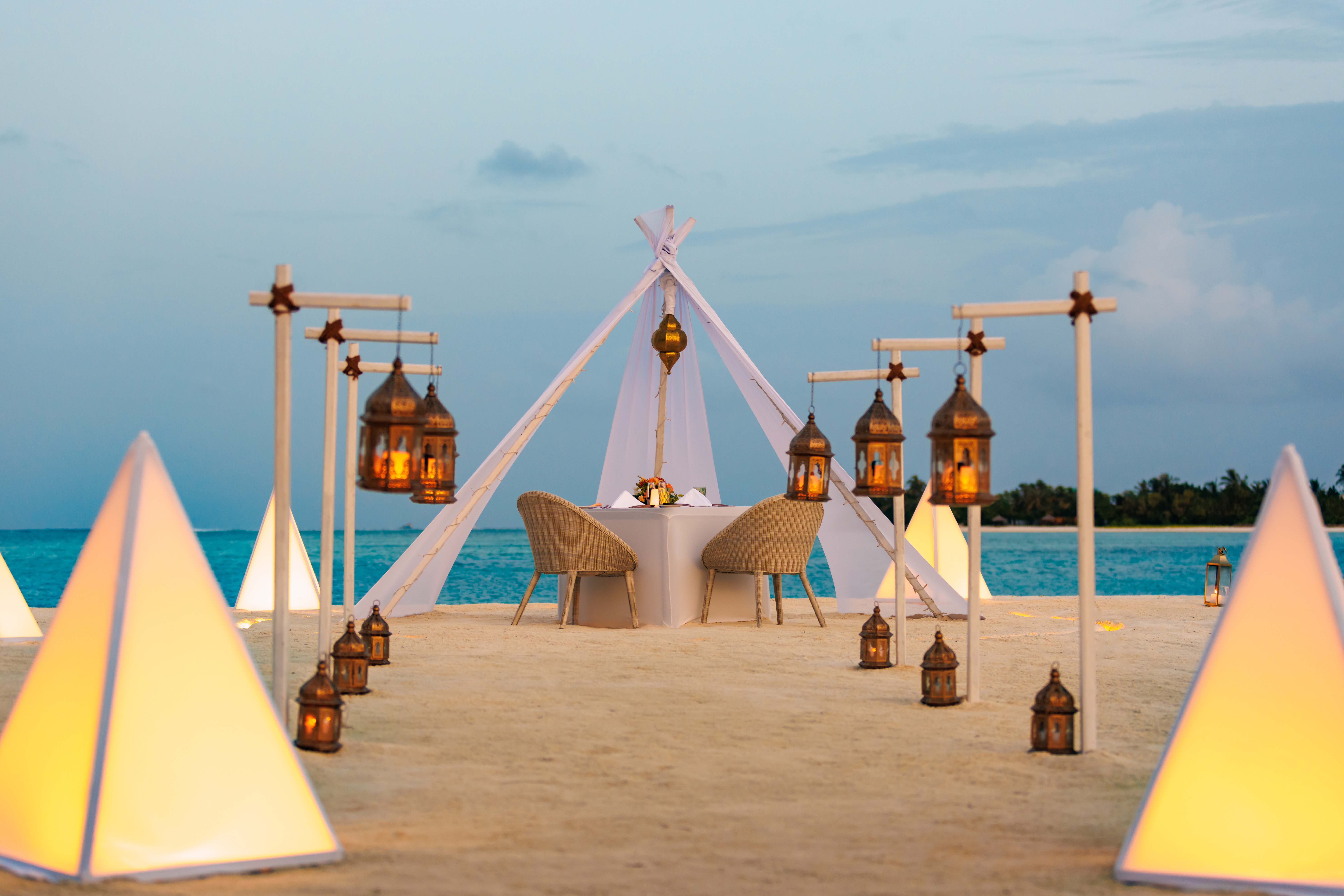Private beachfront dining setup at OZEN LIFE MAADHOO, featuring an elegantly arranged table for two in a secluded setting designed for a personalised Dine by Design experience.