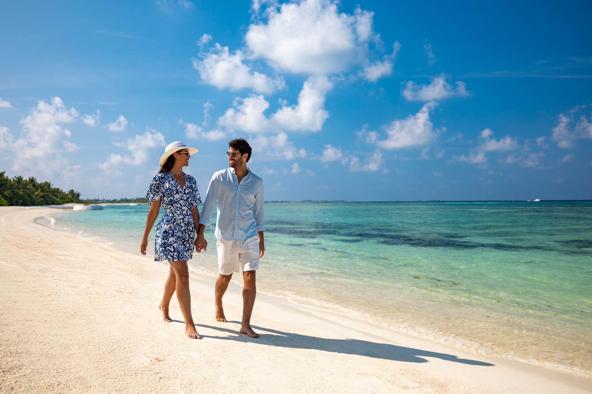Guests walking along the beach at OZEN LIFE MAADHOO, enjoying the island surroundings, sandy shoreline and views across South Malé Atoll.