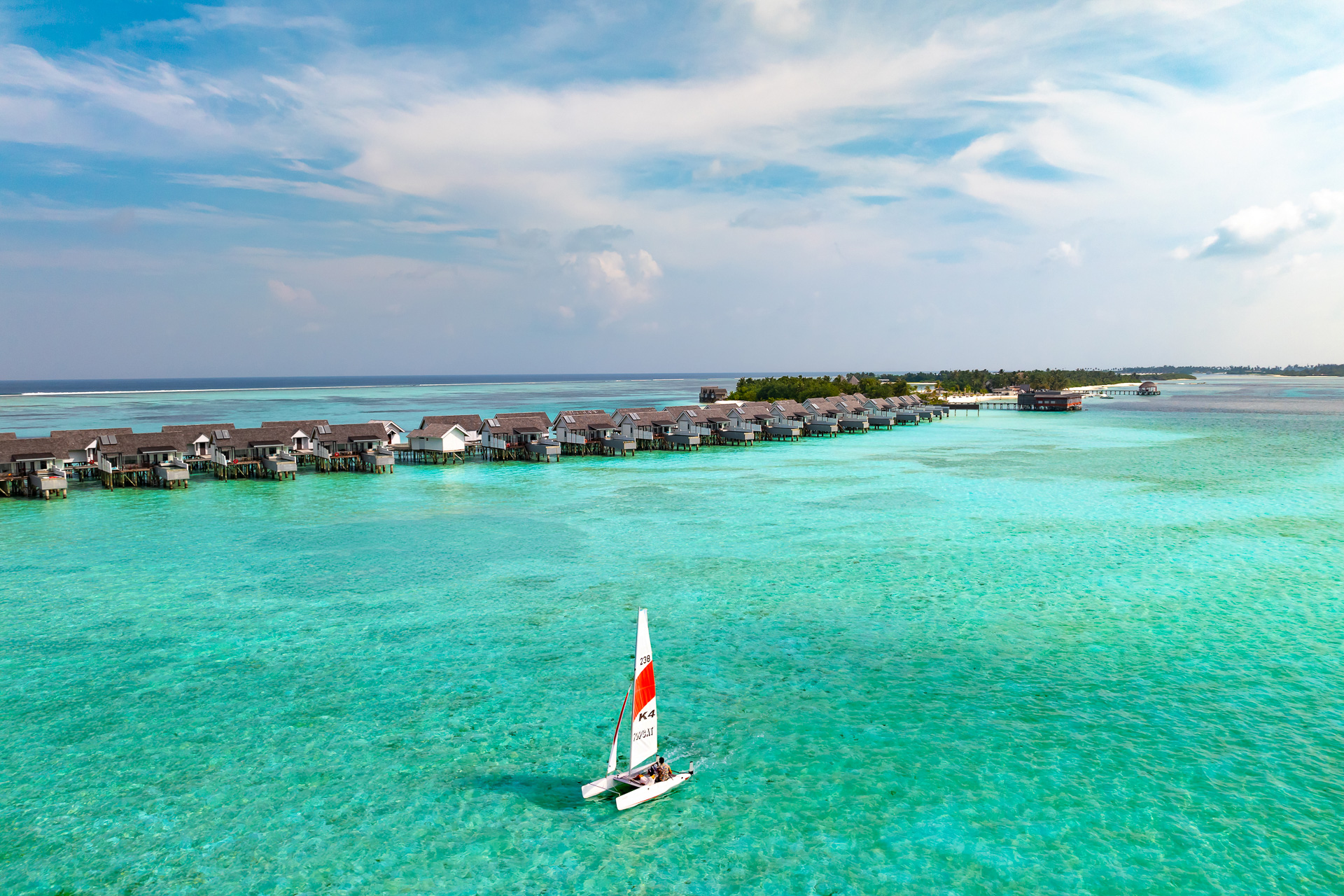 Guests sailing a catamaran in the waters surrounding OZEN LIFE MAADHOO, enjoying views across South Malé Atoll during a watersports experience.